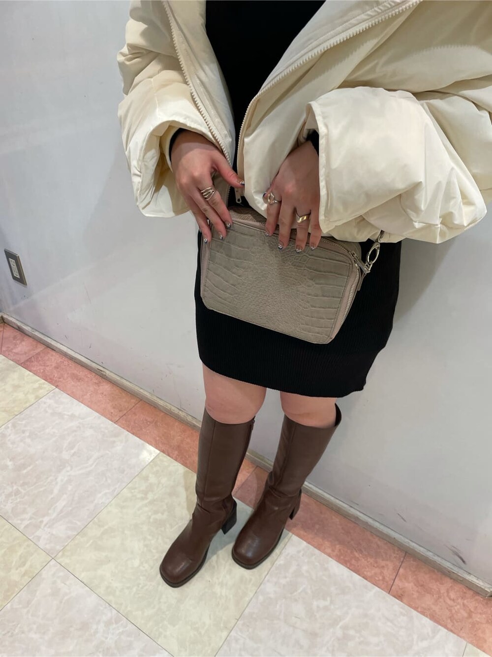 ホワイト系のダウンベスト、ベージュ系のショルダーバッグ、ホワイト系のダウンジャケット/コートを着用したレディースの秋コーディネートの3枚目の写真