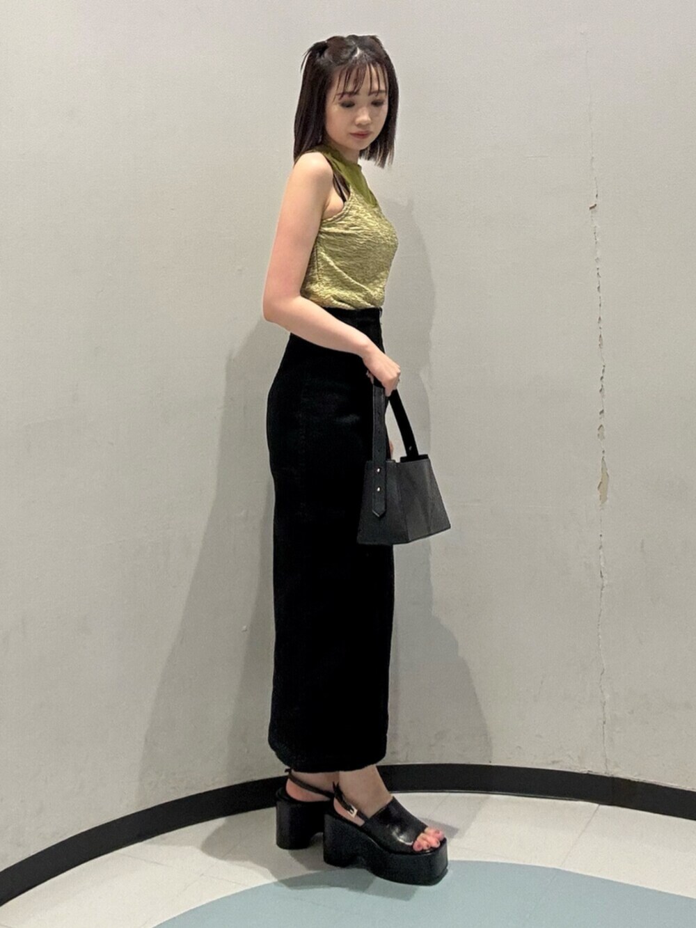 ブラック系のサンダル、グリーン系のタンクトップ、ブラック系のハンドバッグを着用したレディースの夏コーディネートの2枚目の写真