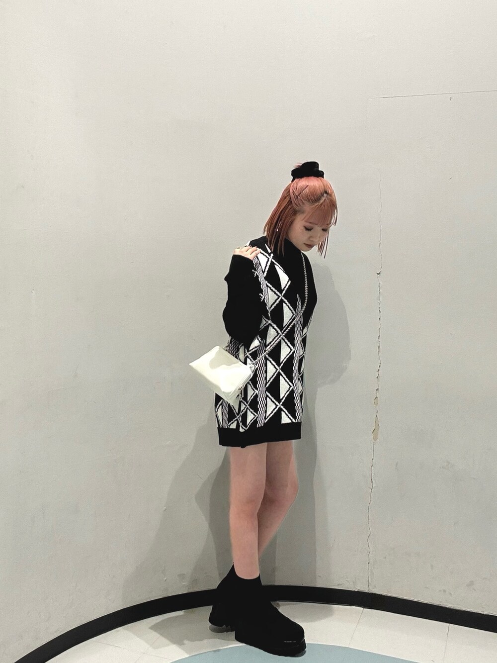 ブラック系のブーツ、ホワイト系のハンドバッグ、その他のベストを着用したレディースの冬コーディネートの2枚目の写真