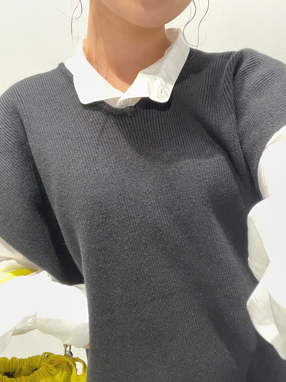 イエロー系のハンドバッグ、ブラック系のワンピースを着用したレディースの夏コーディネートの6枚目の写真