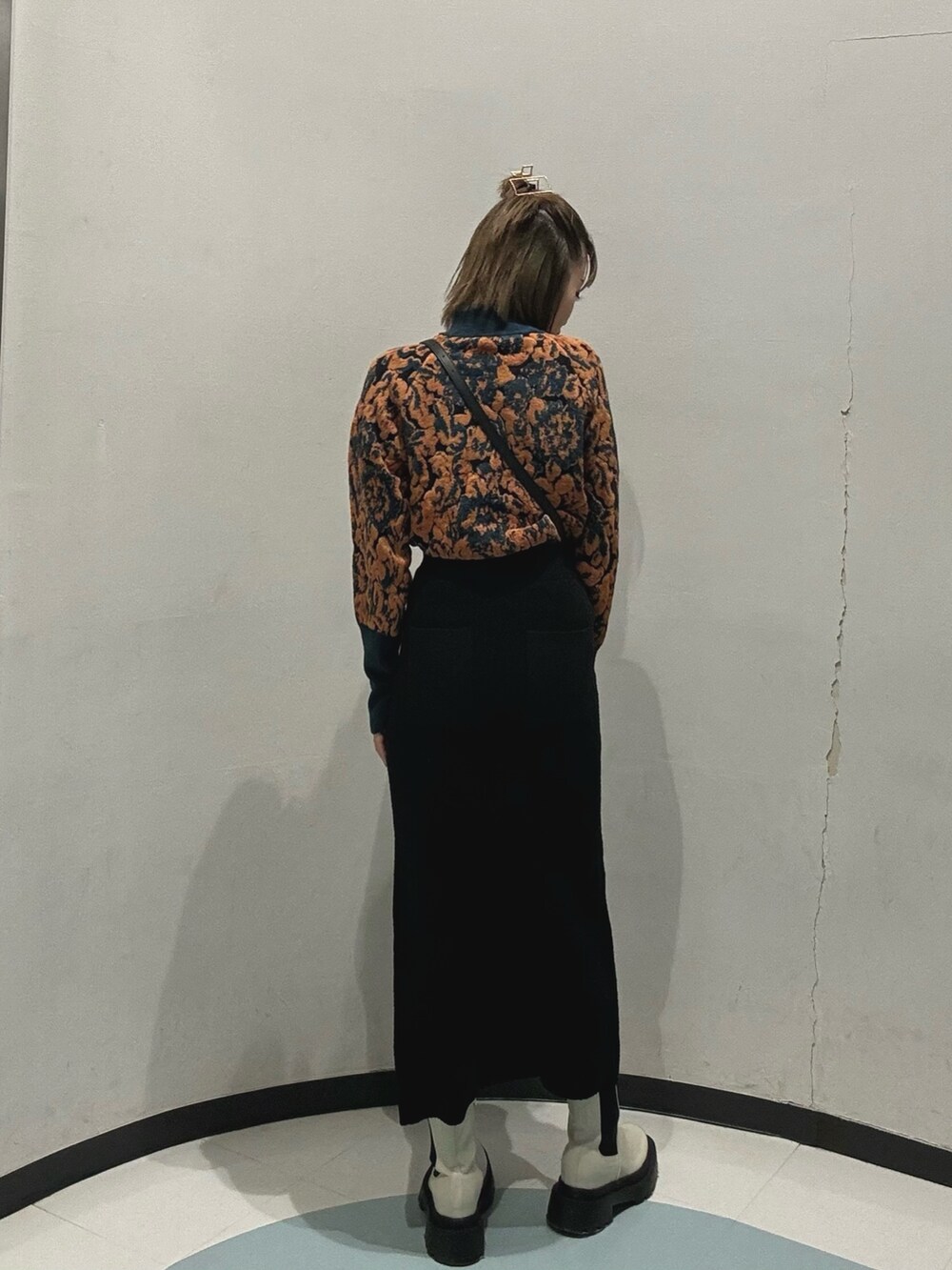 ブラック系のスカート、グリーン系のニット/セーター、ブラック系のハンドバッグを着用したレディースの冬コーディネートの2枚目の写真