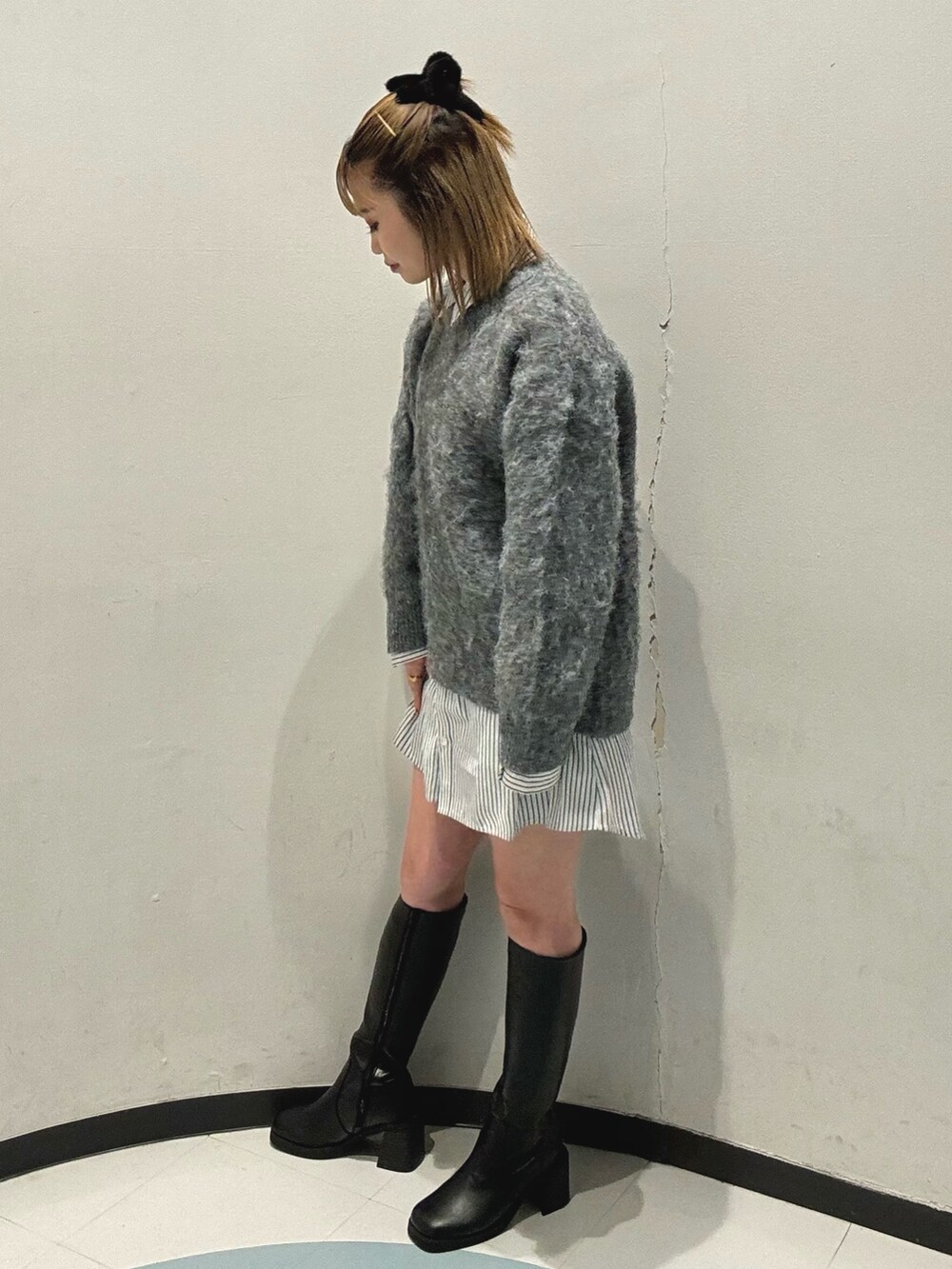 ブラック系のハンドバッグ、グレー系のニット/セーター、ブラック系のブーツを着用したレディースの秋コーディネートの4枚目の写真