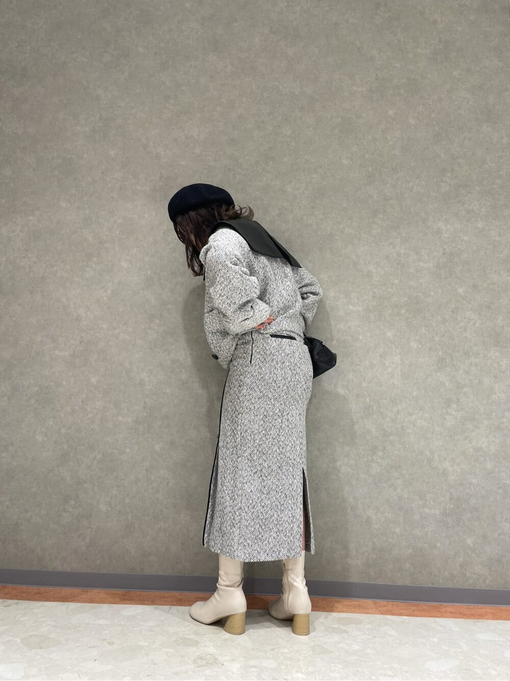 ホワイト系のブーツ、ブラック系のハンドバッグ、ホワイト系のスカートを着用したレディースの秋コーディネートの2枚目の写真