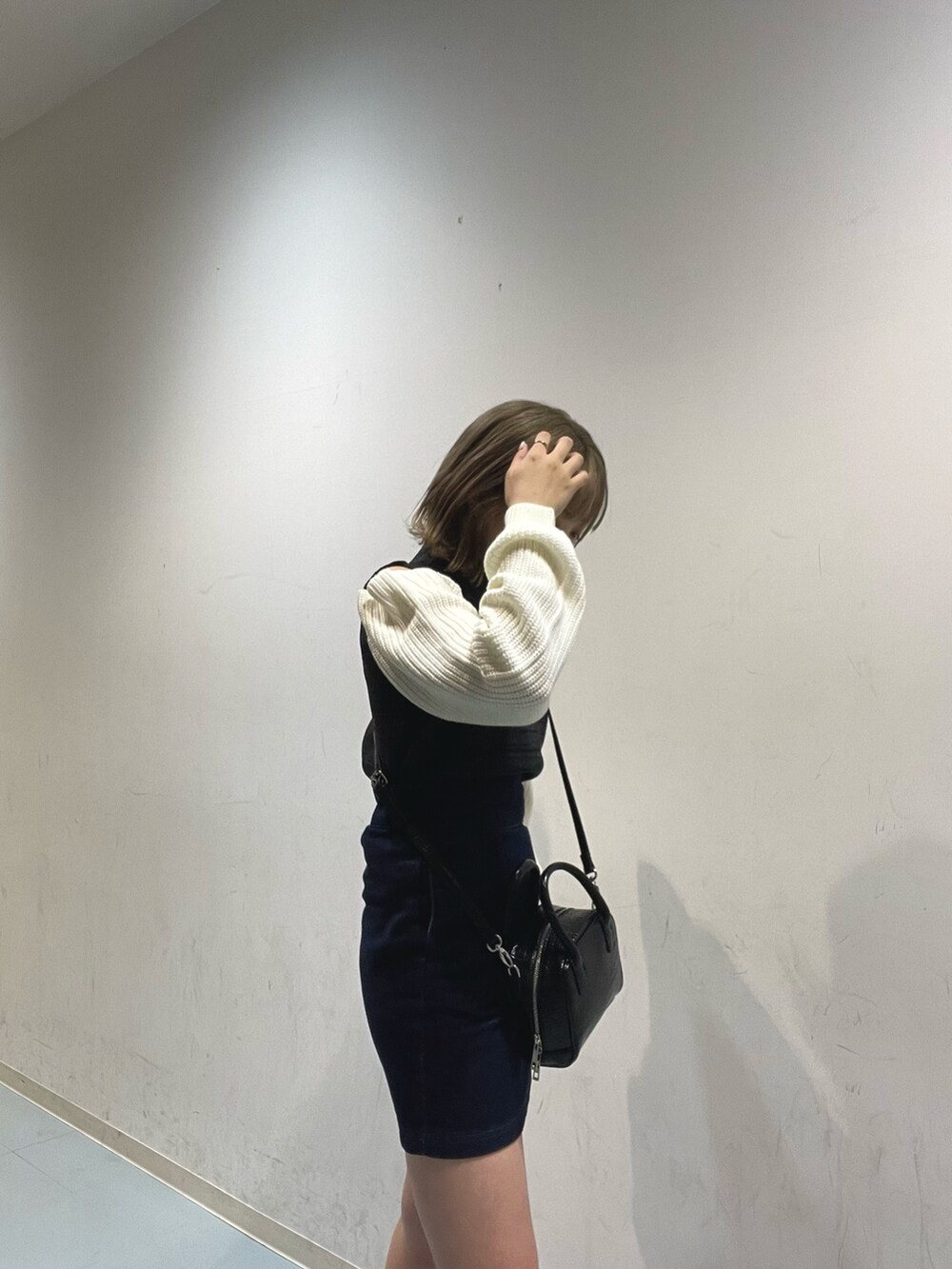 ブラック系のボストンバッグ、ブラック系のニット/セーター、ブラック系のブーツを着用したレディースの秋コーディネートの4枚目の写真