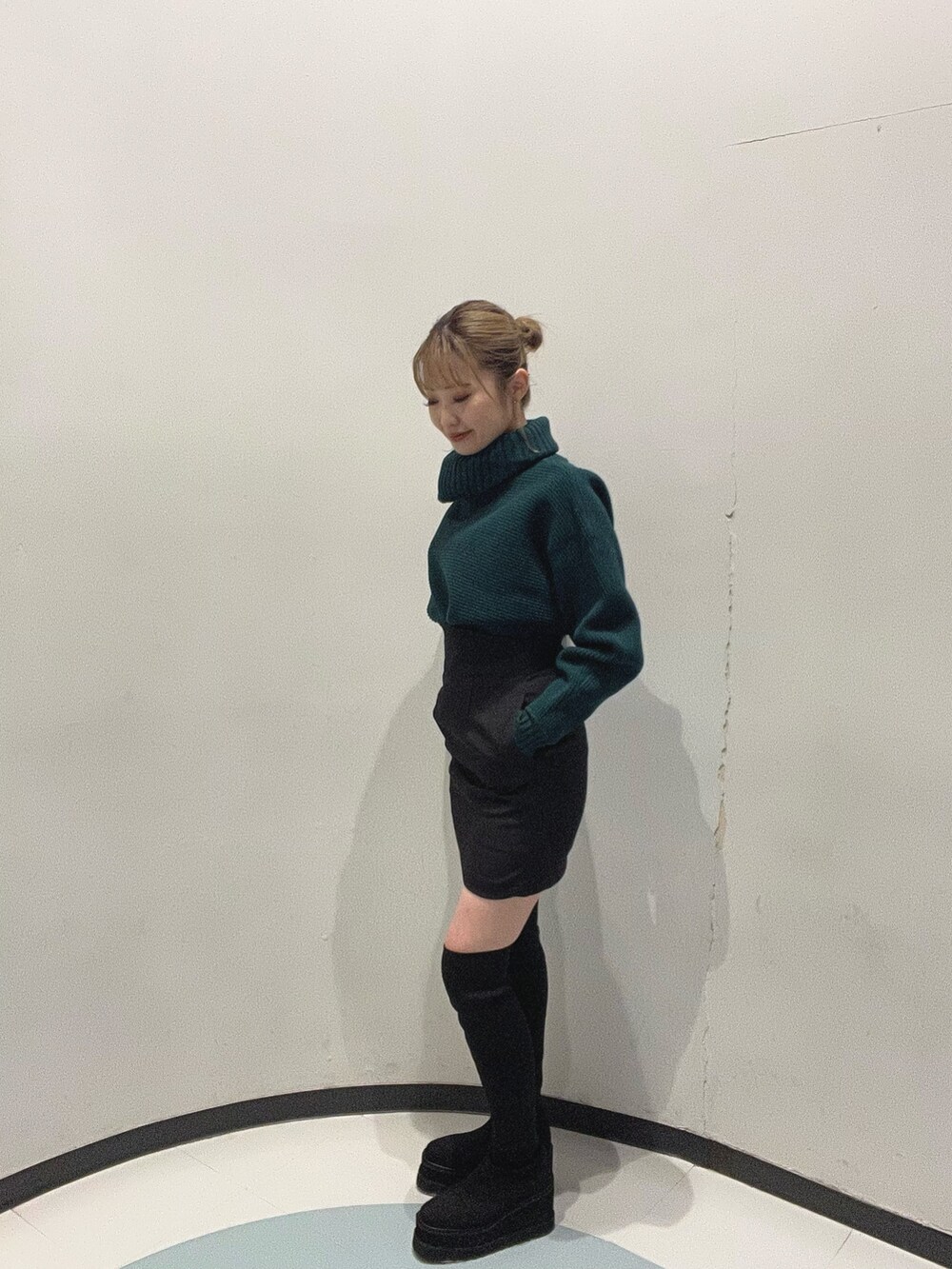 グリーン系のニット/セーター、ブラック系のブーツ、ブラック系のスカートを着用したレディースの秋コーディネートの5枚目の写真