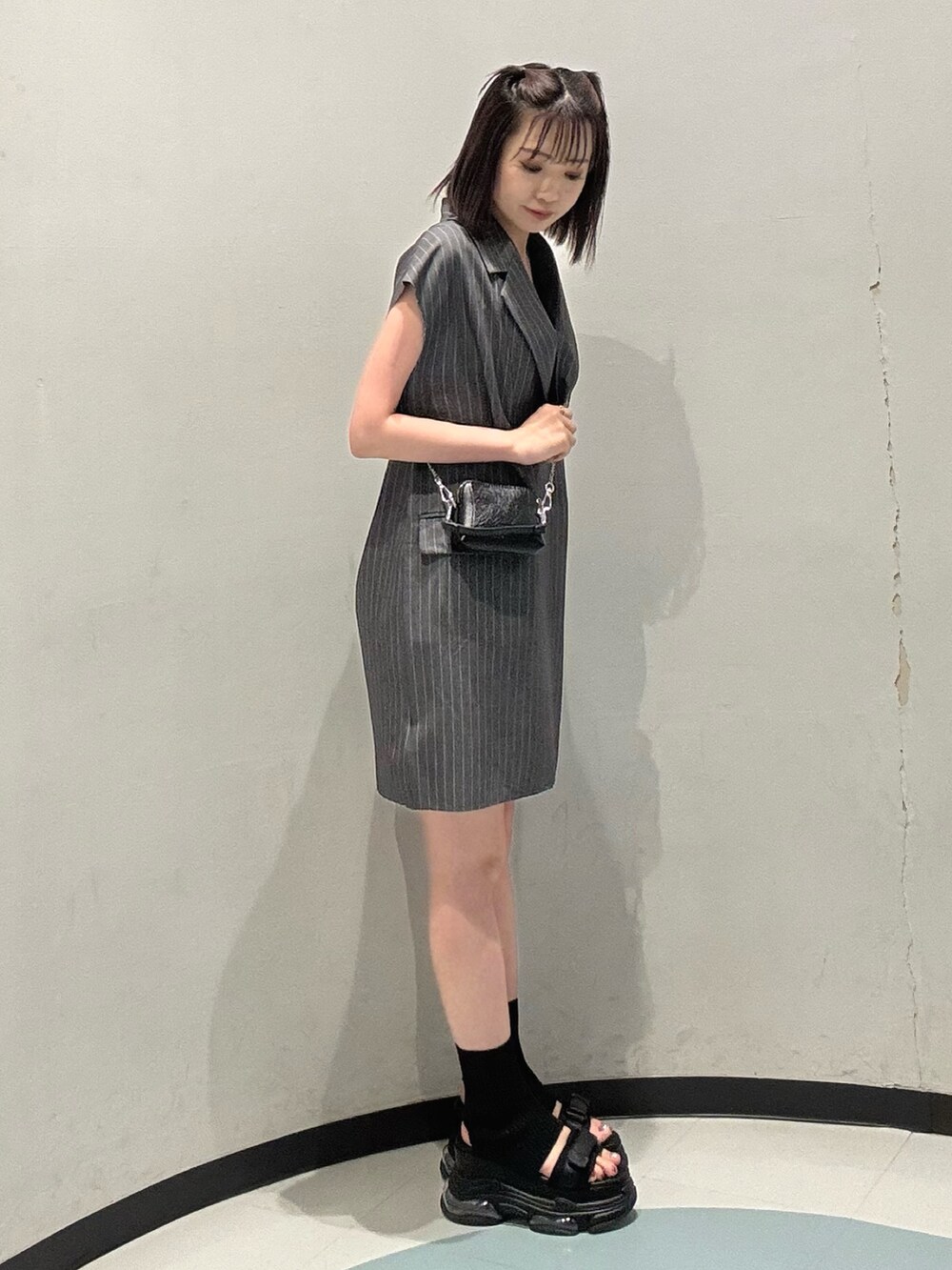 ブラック系のショルダーバッグ、ブラック系のサンダル、グレー系のワンピースを着用したレディースの夏コーディネートの2枚目の写真