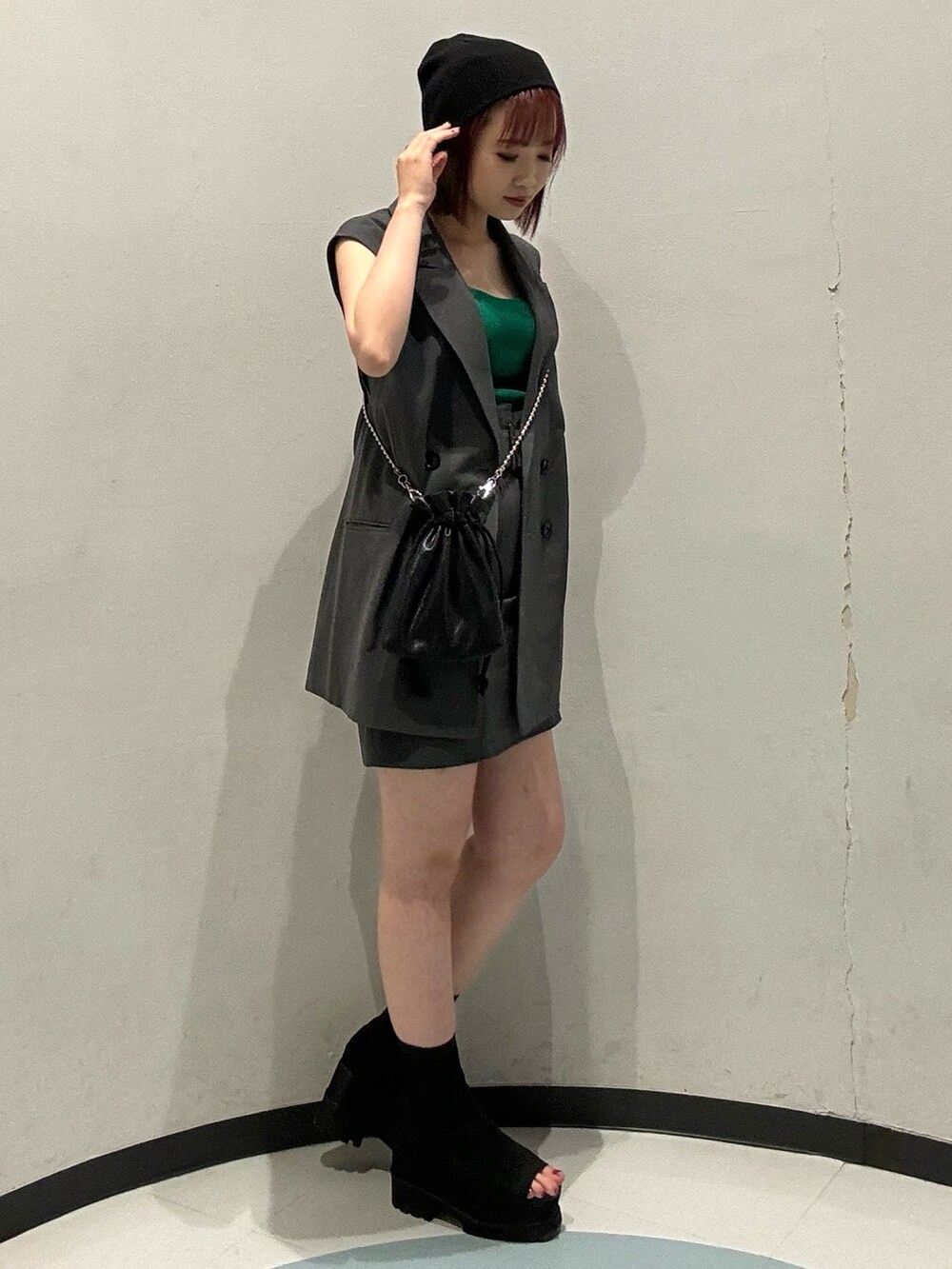 ブラック系のショルダーバッグ、グレー系のベスト、ブラック系のブーツを着用したレディースの夏コーディネートの2枚目の写真