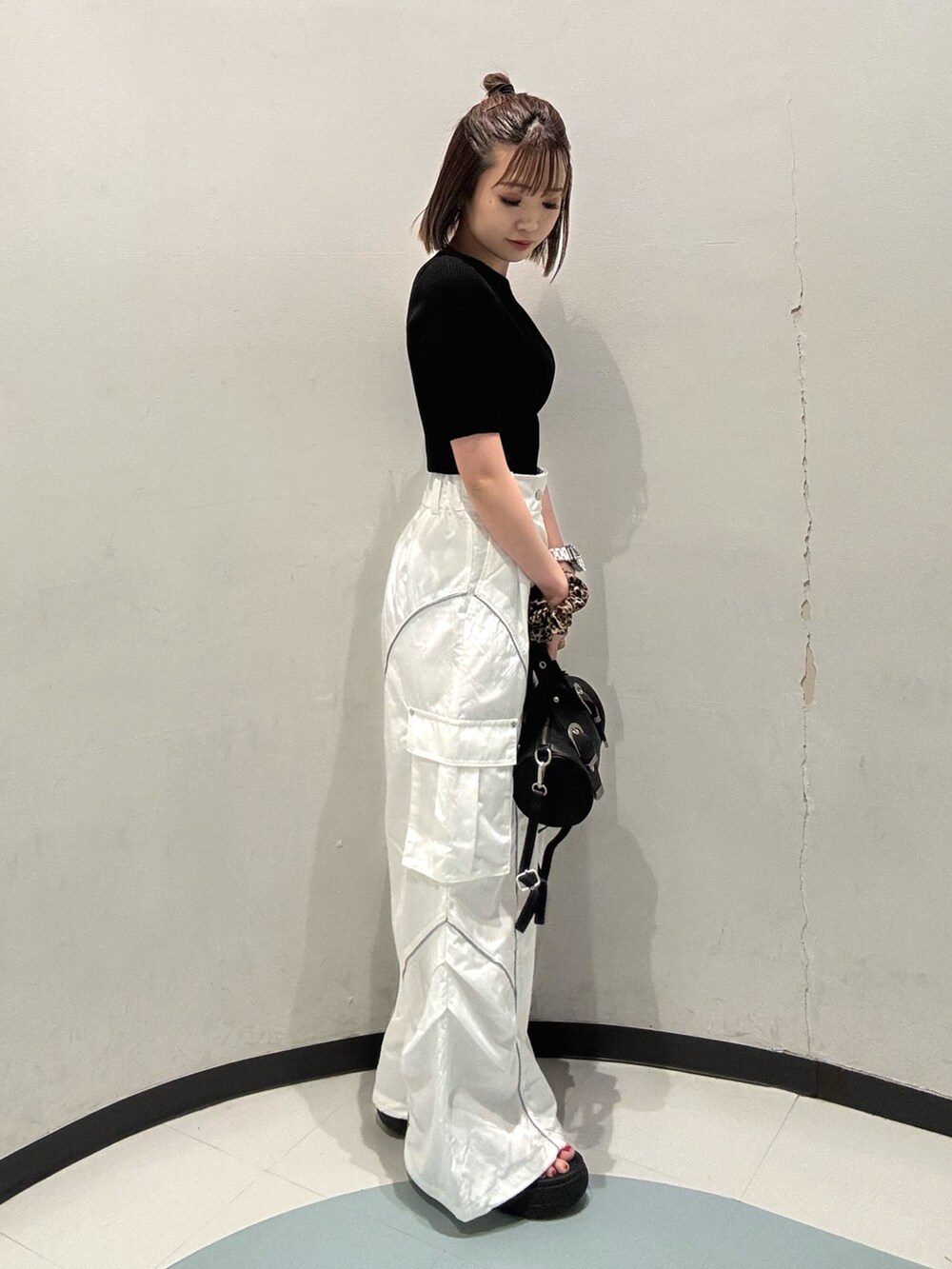 ブラック系のニット/セーター、ホワイト系のカーゴパンツ、ブラック系のサンダルを着用したレディースの春コーディネートの2枚目の写真
