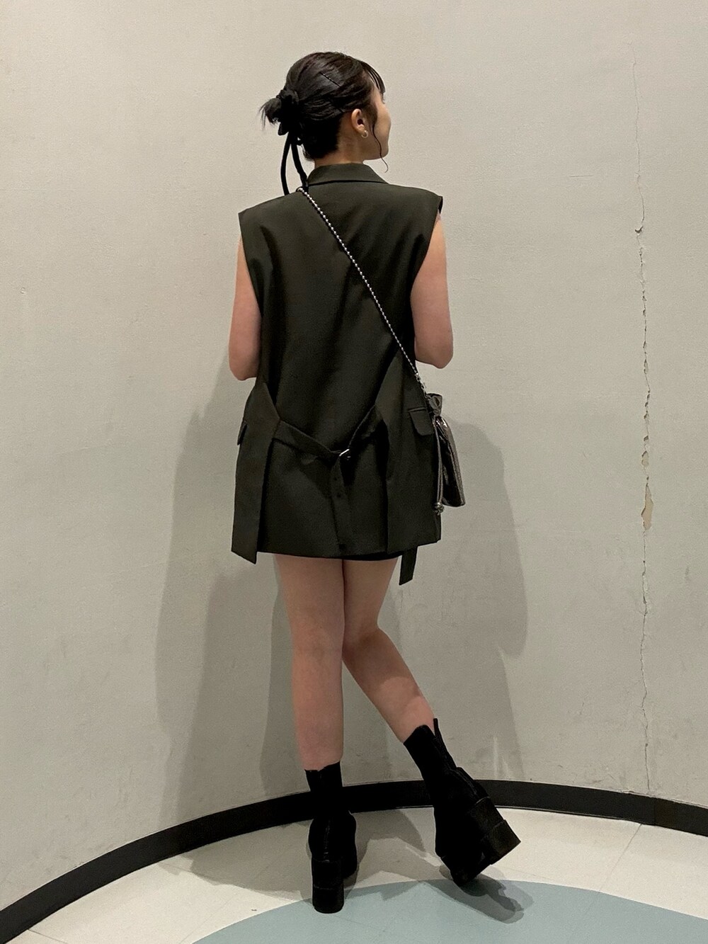 グレー系のベスト、グレー系のスカート、グレー系のショルダーバッグを着用したレディースの春コーディネートの3枚目の写真