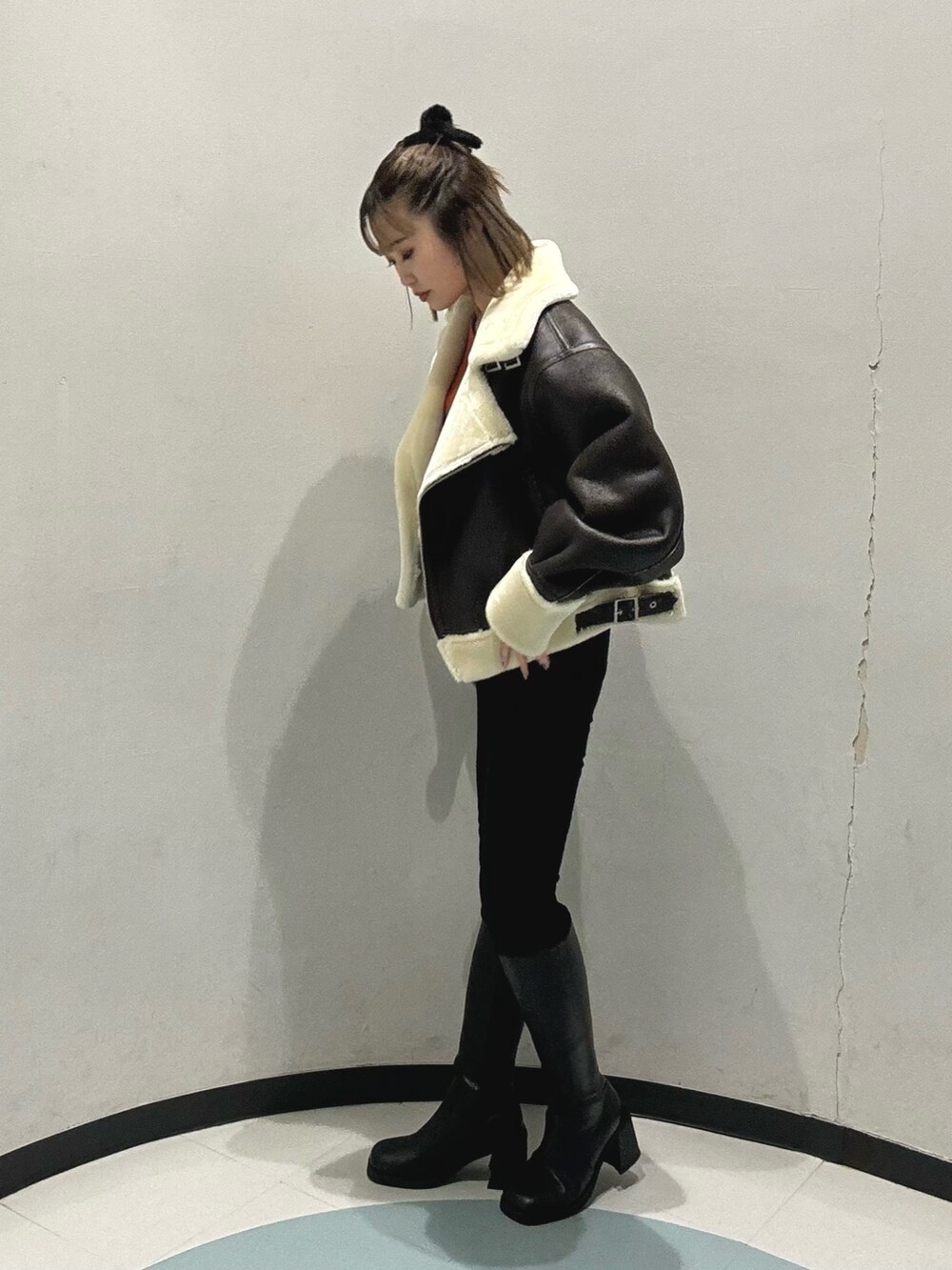 ブラック系のブーツ、ブラック系のハンドバッグ、ブラウン系のムートンコートを着用したレディースの冬コーディネートの3枚目の写真