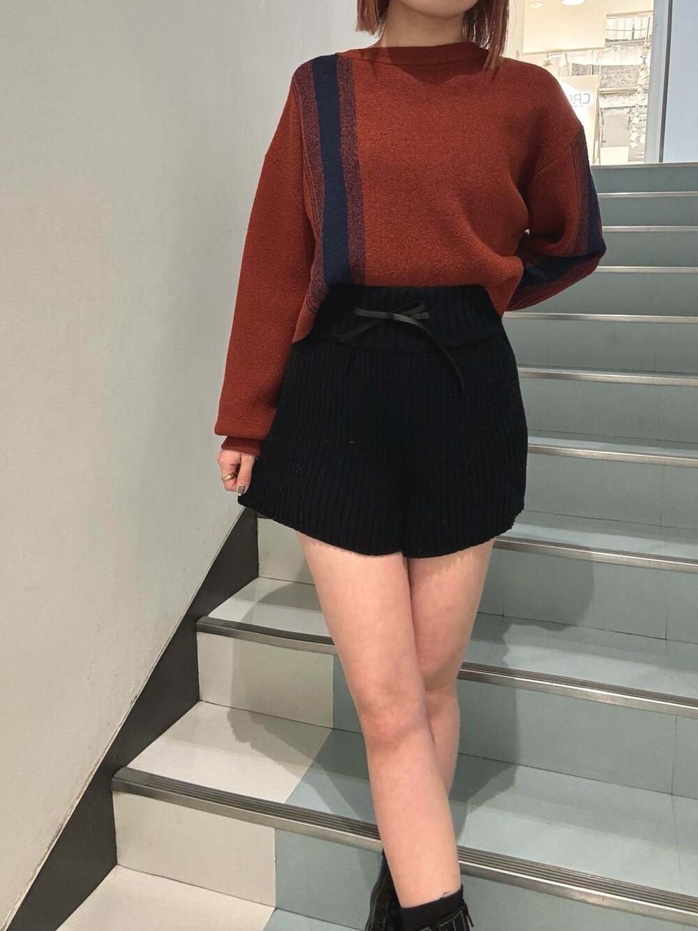 ブラック系のその他パンツ、オレンジ系のニット/セーター、グレー系のブルゾンを着用したレディースの冬コーディネートの7枚目の写真