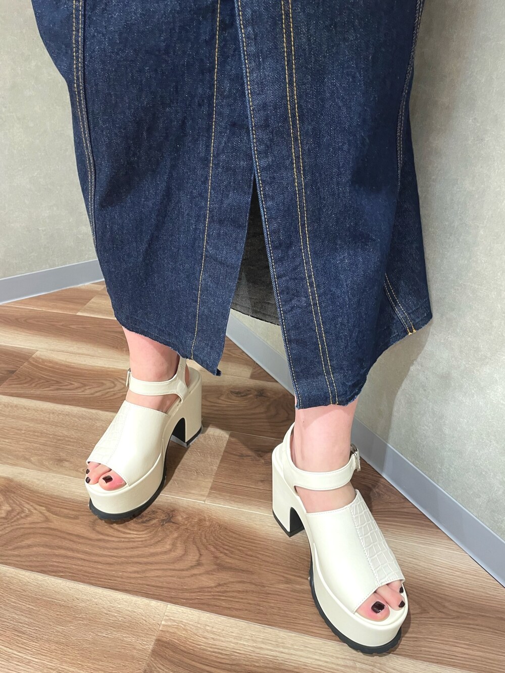 オレンジ系のカーディガン/ボレロ、ホワイト系のデニムスカート、ホワイト系のサンダルを着用したレディースの春コーディネートの7枚目の写真