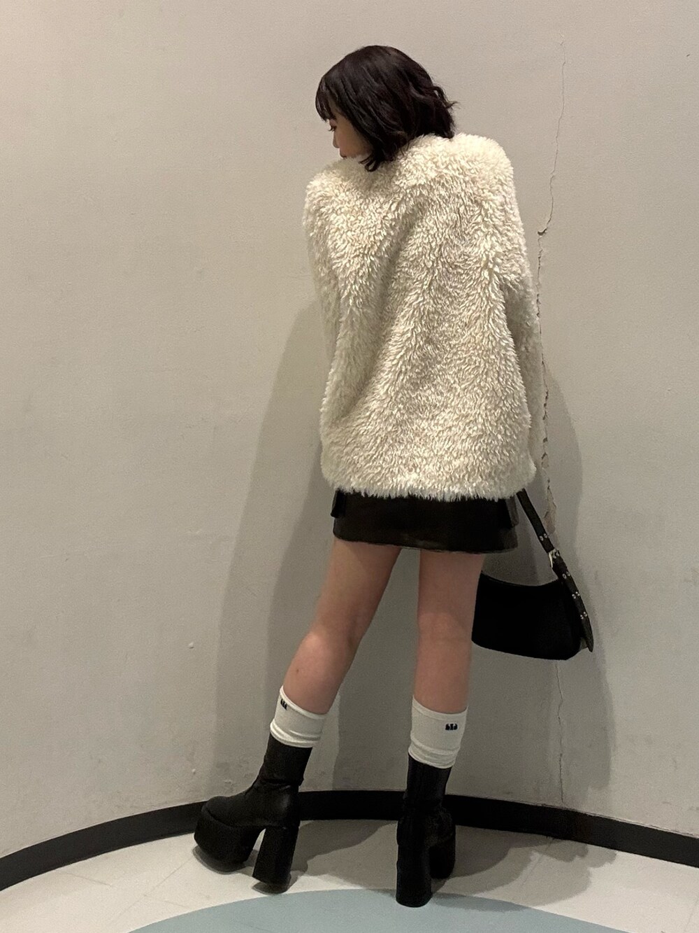 ブラック系のハンドバッグ、ブラウン系のスカート、ブラック系のニット/セーターを着用したレディースの冬コーディネートの3枚目の写真