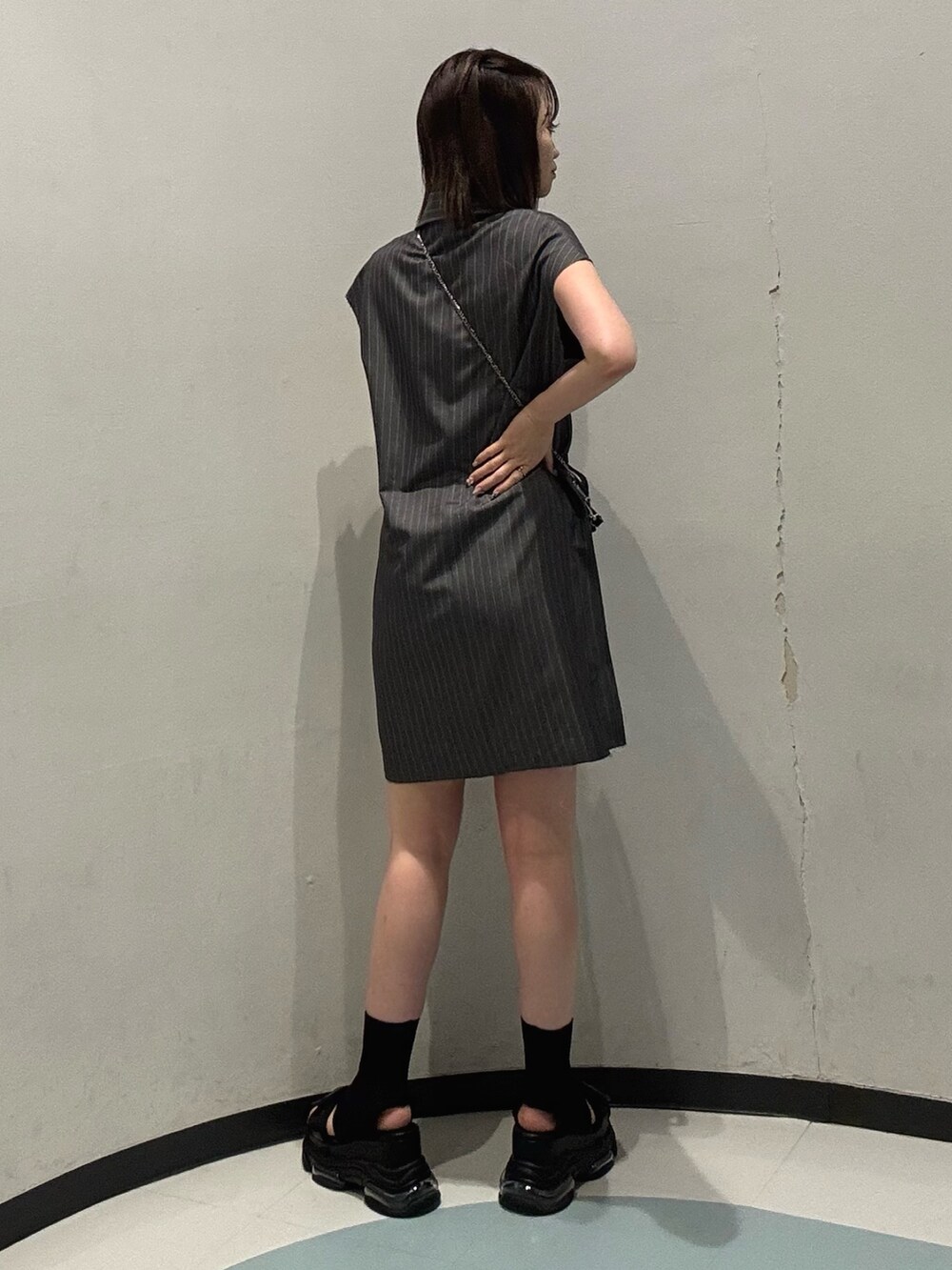 ブラック系のショルダーバッグ、ブラック系のサンダル、グレー系のワンピースを着用したレディースの夏コーディネートの3枚目の写真