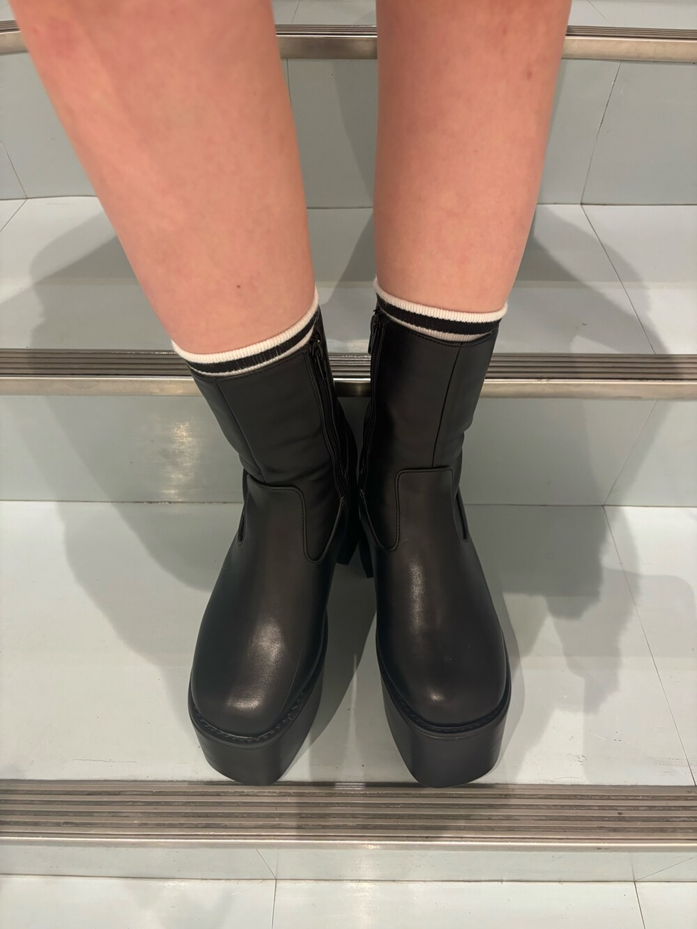 ホワイト系のニット/セーター、ブラウン系のスカート、ブラック系のブーツを着用したレディースの秋コーディネートの7枚目の写真