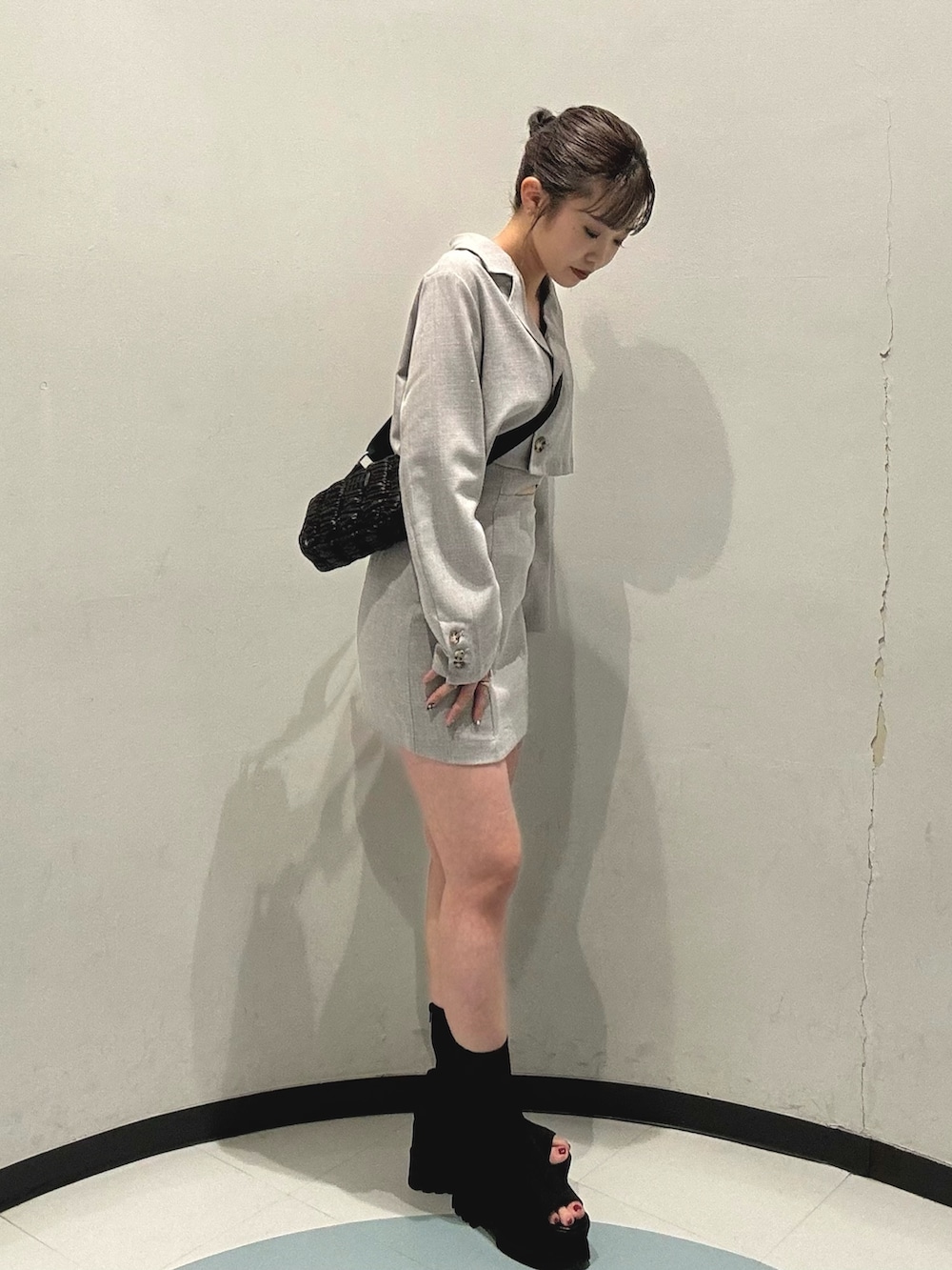 ブラック系のショルダーバッグ、グレー系のワンピース、ブラック系のブーツを着用したレディースの春コーディネートの2枚目の写真