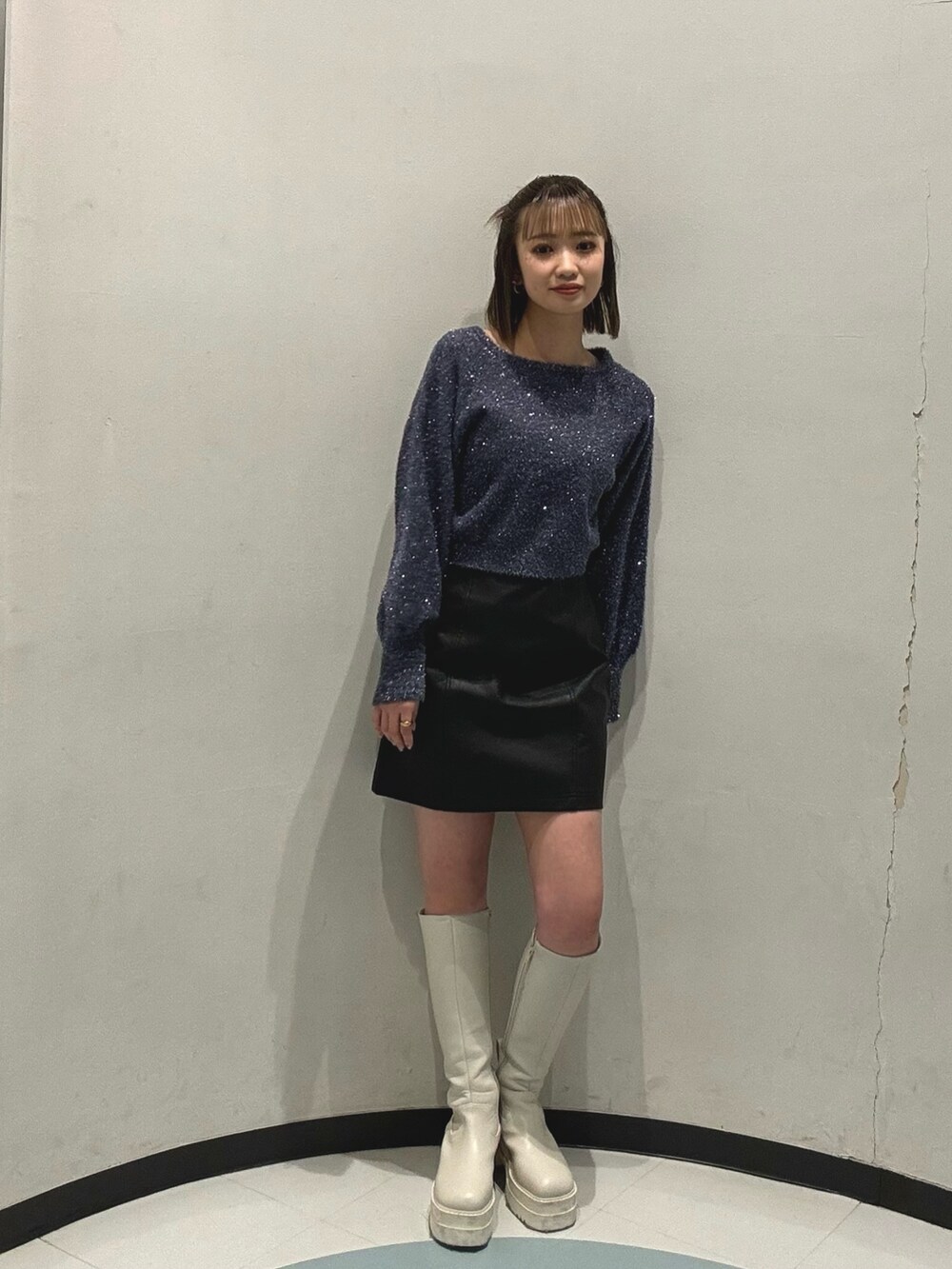 ブルー系のニット/セーター、ホワイト系のブルゾン、ブラック系のスカートを着用したレディースの冬コーディネートの6枚目の写真