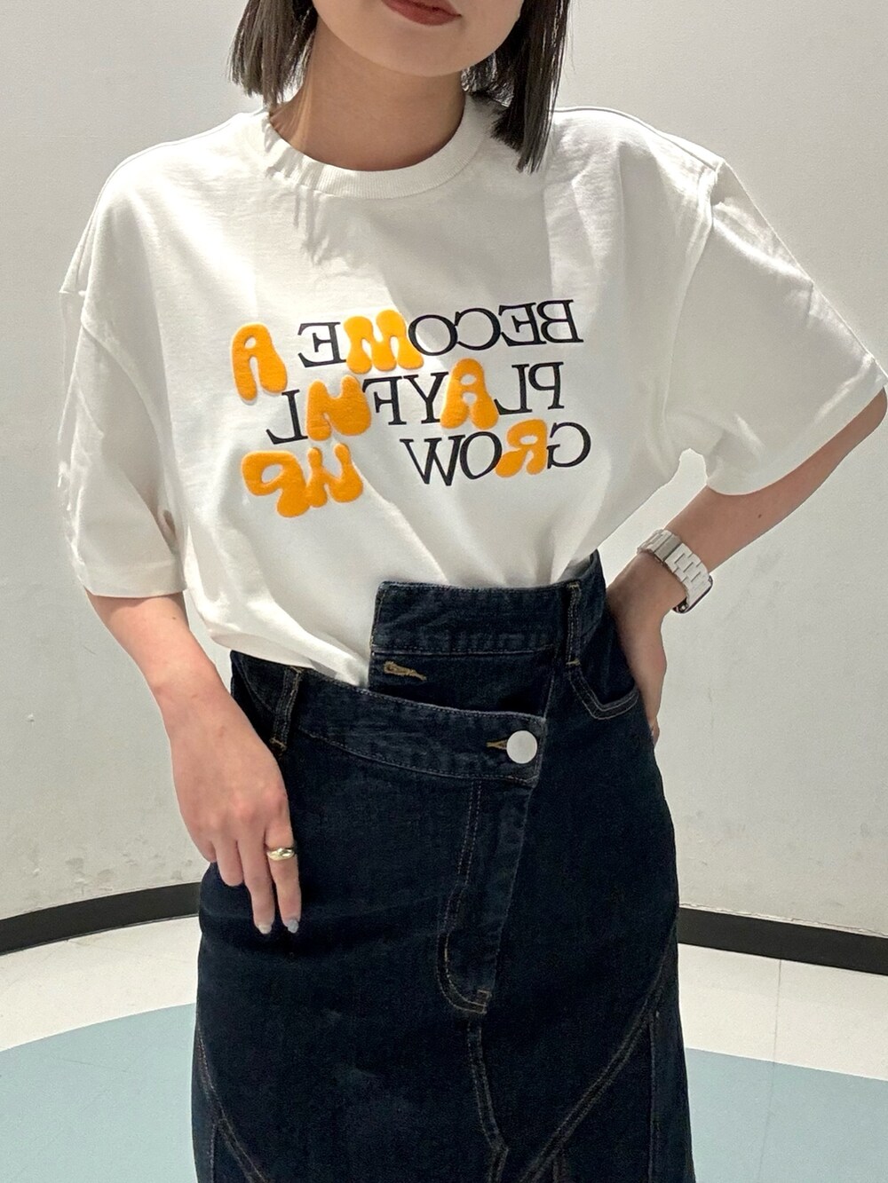 ブルー系のデニムスカート、ホワイト系のTシャツ/カットソー、シルバー系のサンダルを着用したレディースの春コーディネートの4枚目の写真