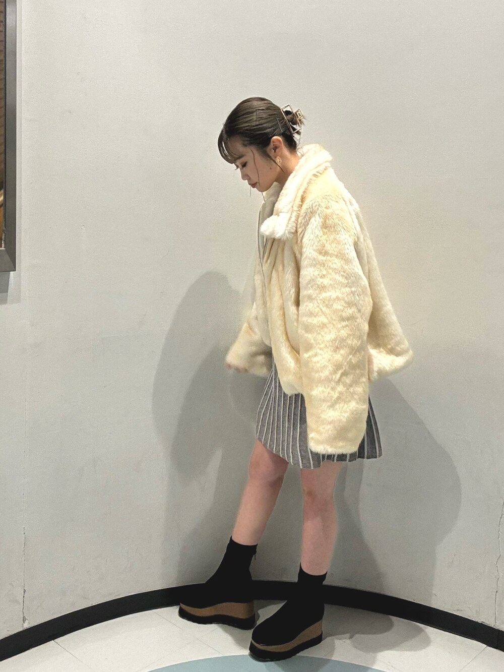 ホワイト系のブルゾン、ホワイト系のハンドバッグ、ブラック系のブーツを着用したレディースの冬コーディネートの2枚目の写真