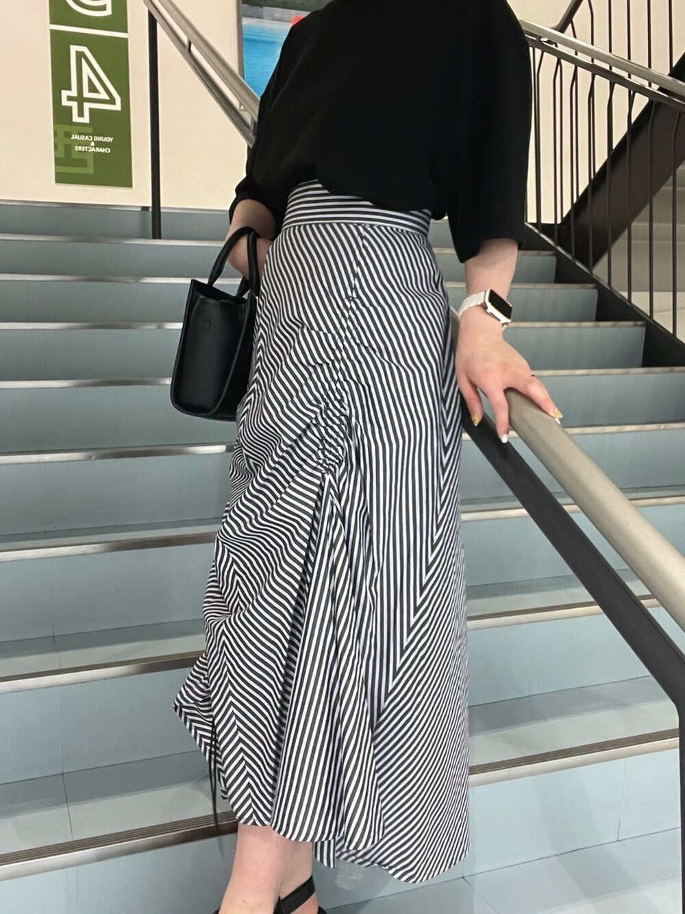 ブラック系のショルダーバッグ、ブラック系のTシャツ/カットソー、ブラック系のサンダルを着用したレディースの春コーディネートの5枚目の写真