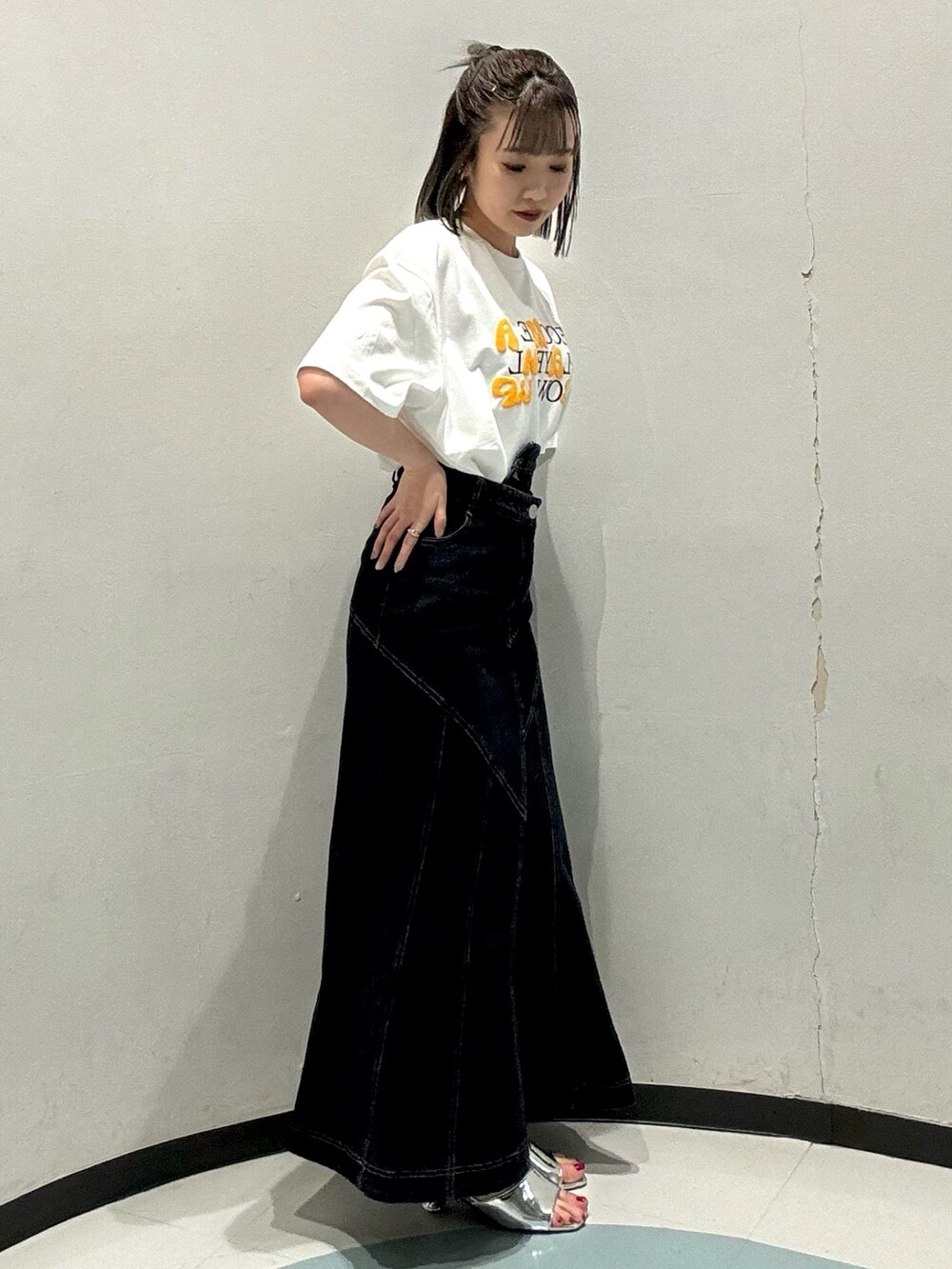 ブルー系のデニムスカート、ホワイト系のTシャツ/カットソー、シルバー系のサンダルを着用したレディースの春コーディネートの2枚目の写真