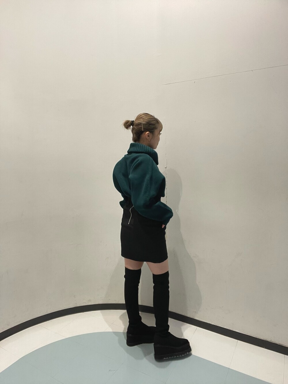 グリーン系のニット/セーター、ブラック系のブーツ、ブラック系のスカートを着用したレディースの秋コーディネートの4枚目の写真