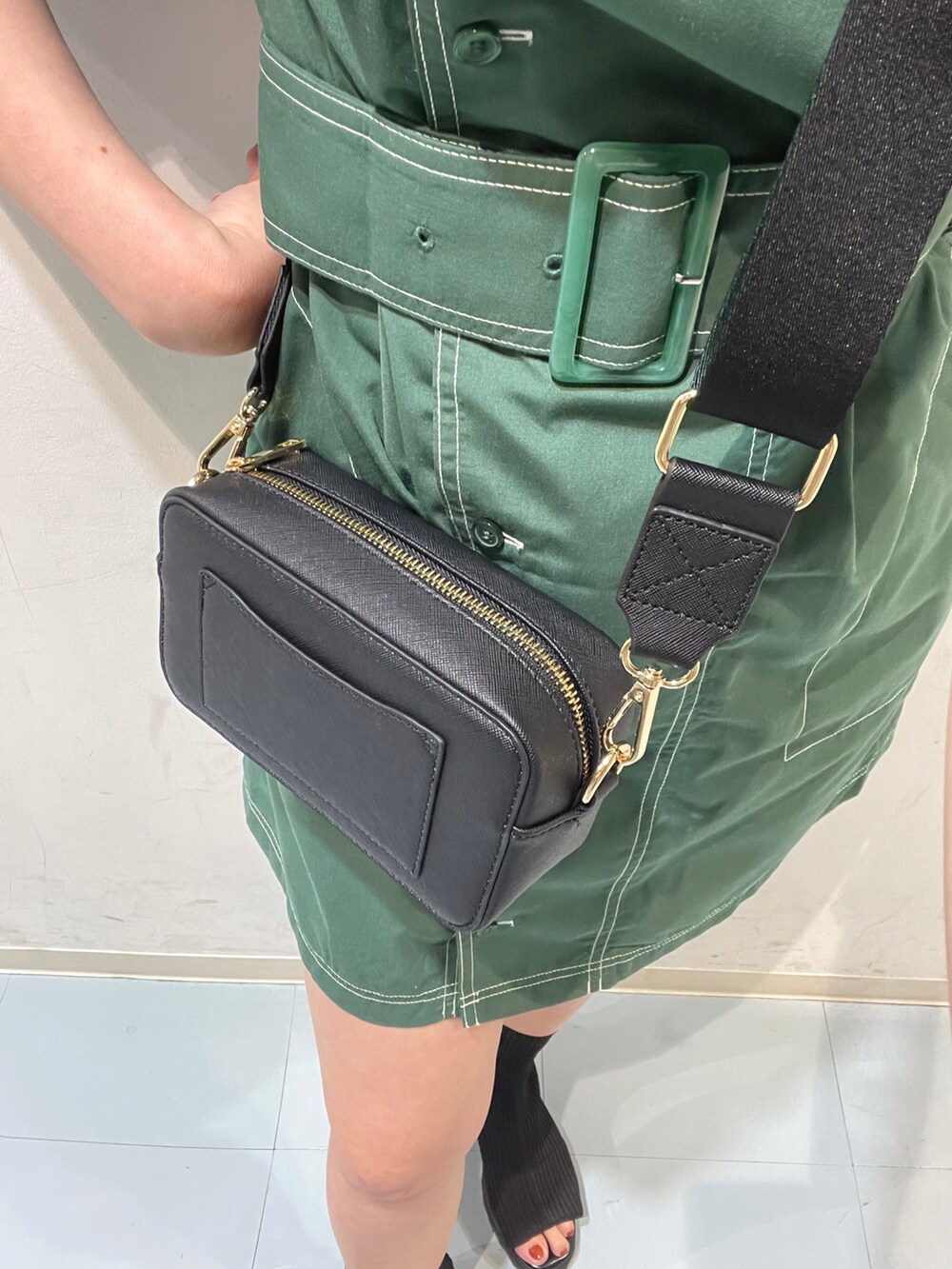 グリーン系のワンピース、ブラック系のショルダーバッグ、ブラック系のブーツを着用したレディースの夏コーディネートの5枚目の写真
