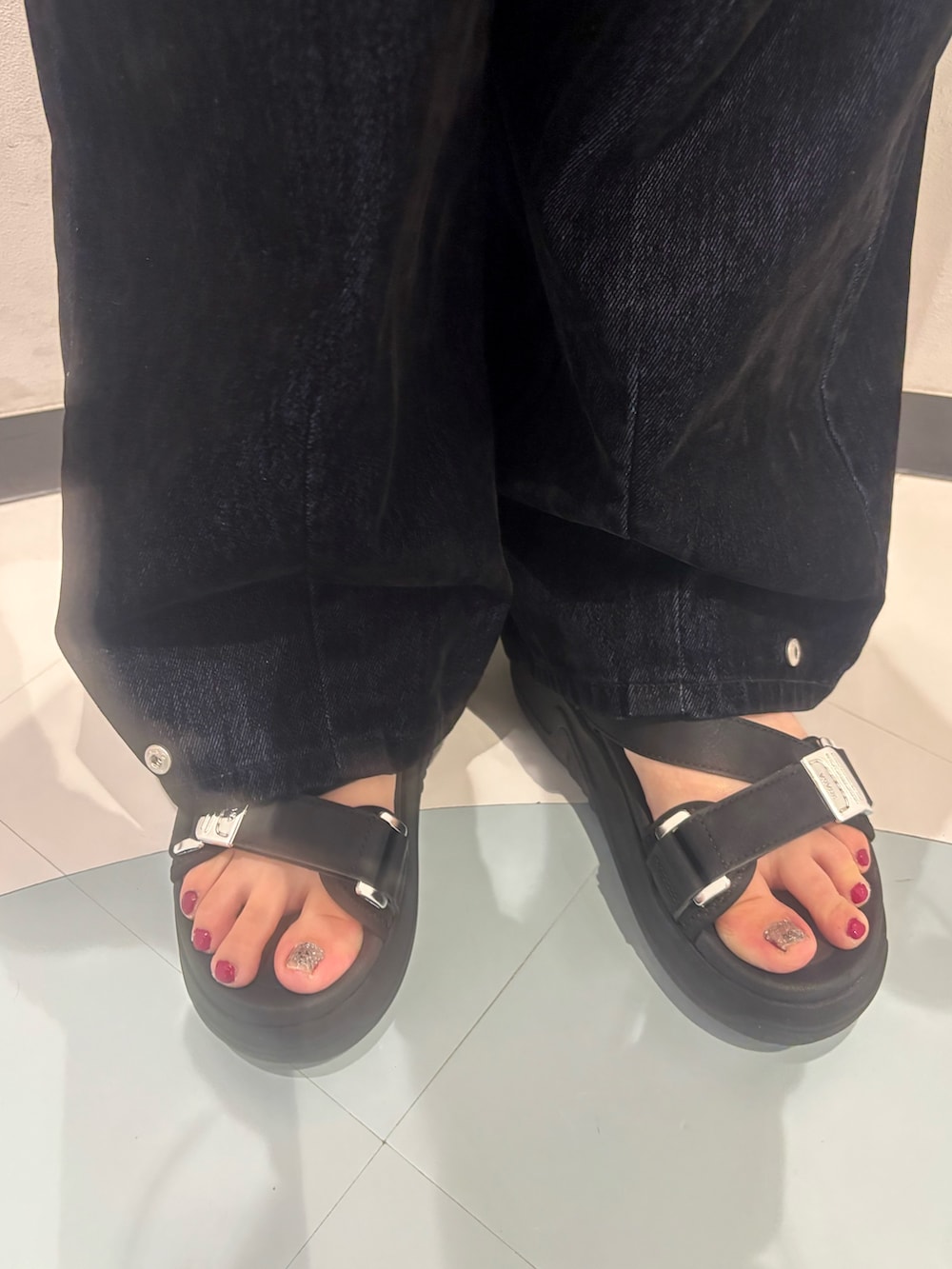 ブラック系のデニムパンツ、ベージュ系のTシャツ/カットソー、ブラック系のサンダルを着用したレディースの夏コーディネートの7枚目の写真