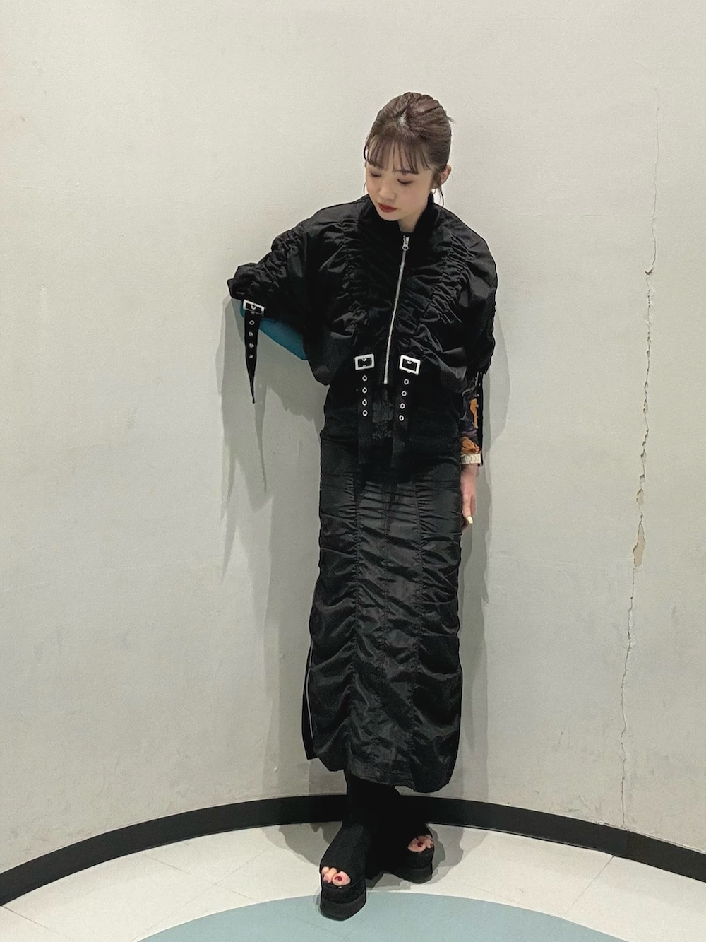 ブラック系のスカート、ホワイト系のハンドバッグ、ブラック系のブルゾンを着用したレディースの春コーディネートの2枚目の写真