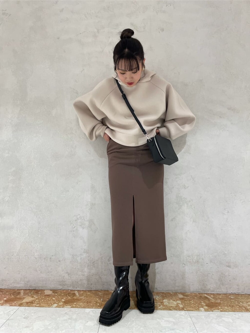 ベージュ系のスカート、ブラック系のショルダーバッグ、ブラック系のブーツを着用したレディースの秋コーディネートの4枚目の写真