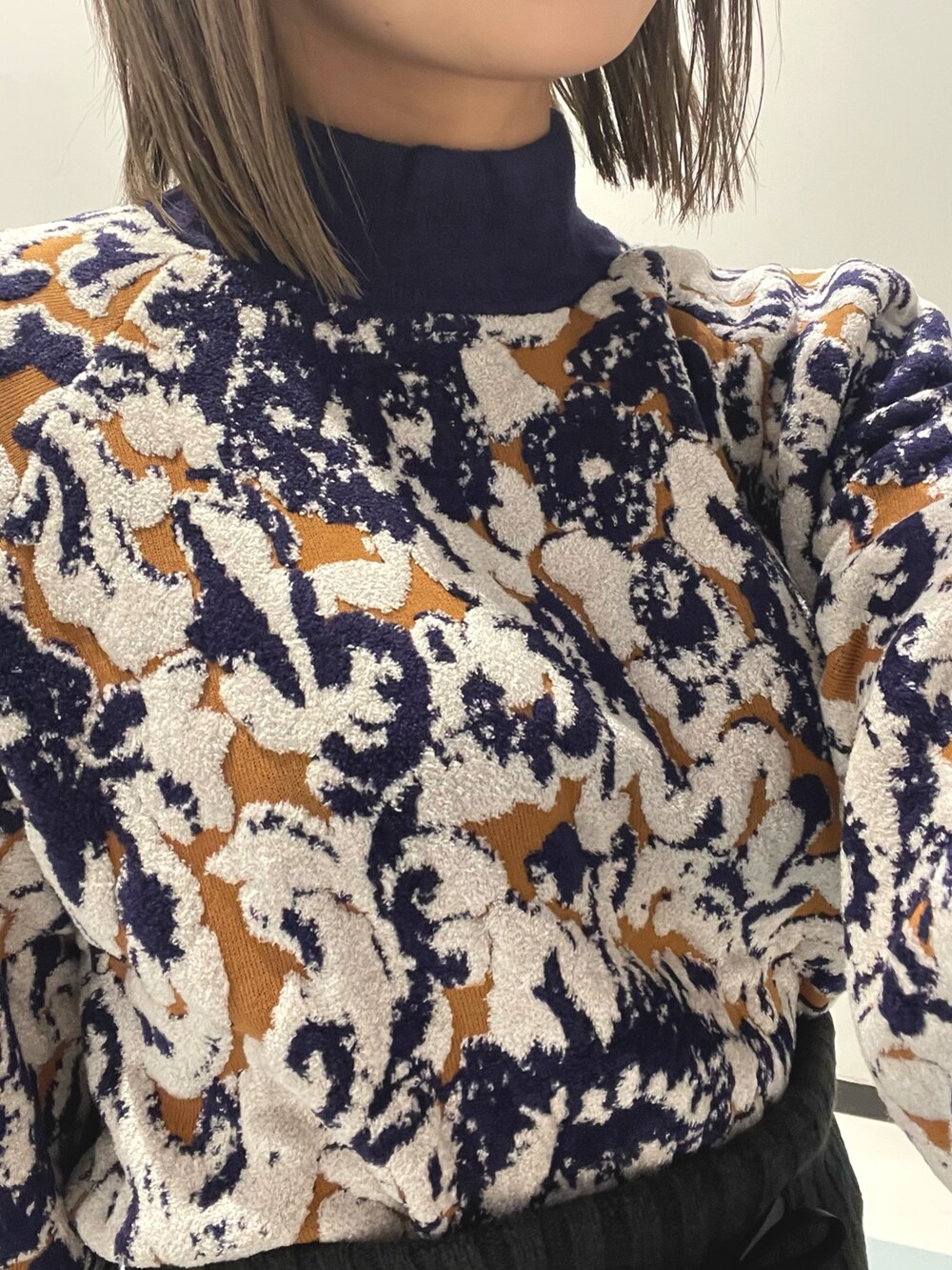 グリーン系のハンドバッグ、ブラック系のダウンベスト、ホワイト系のブーツを着用したレディースの秋コーディネートの6枚目の写真