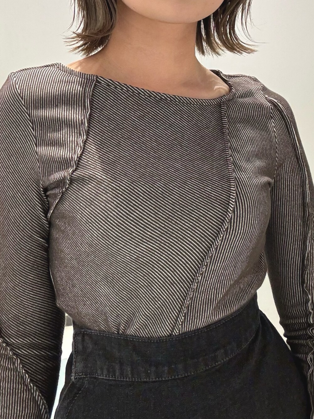 ブラック系のデニムスカート、グレー系のTシャツ/カットソー、ブラック系のハンドバッグを着用したレディースの冬コーディネートの4枚目の写真