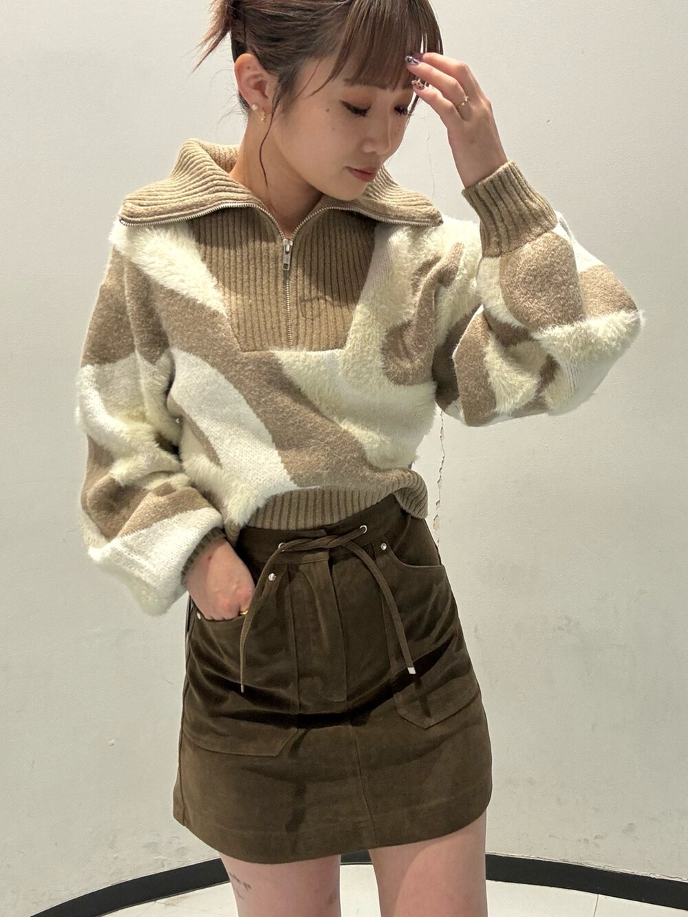 ホワイト系のニット/セーター、ブラウン系のスカート、ブラック系のブーツを着用したレディースの秋コーディネートの4枚目の写真