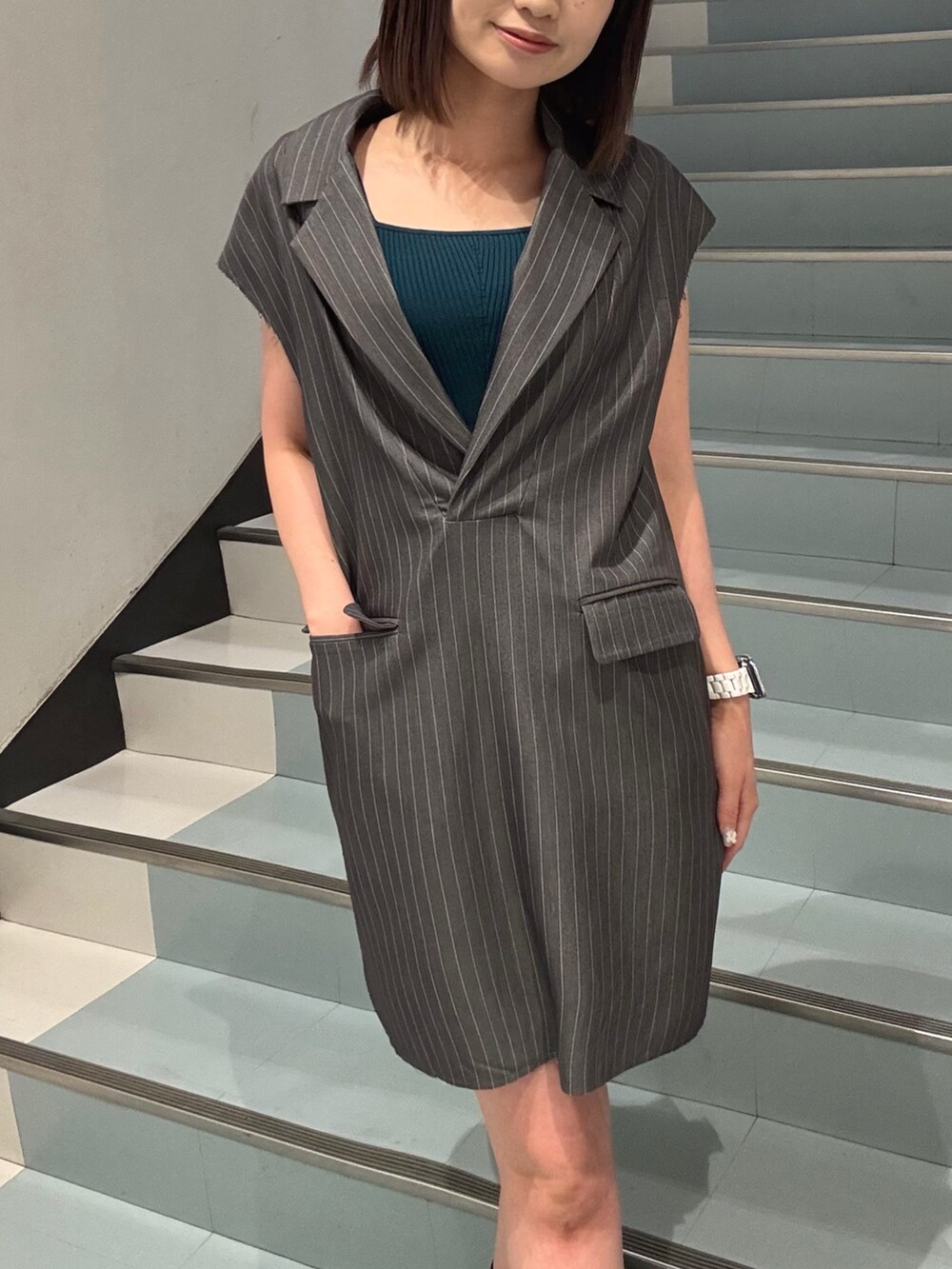 ブラック系のショルダーバッグ、ブラック系のサンダル、グレー系のワンピースを着用したレディースの夏コーディネートの5枚目の写真