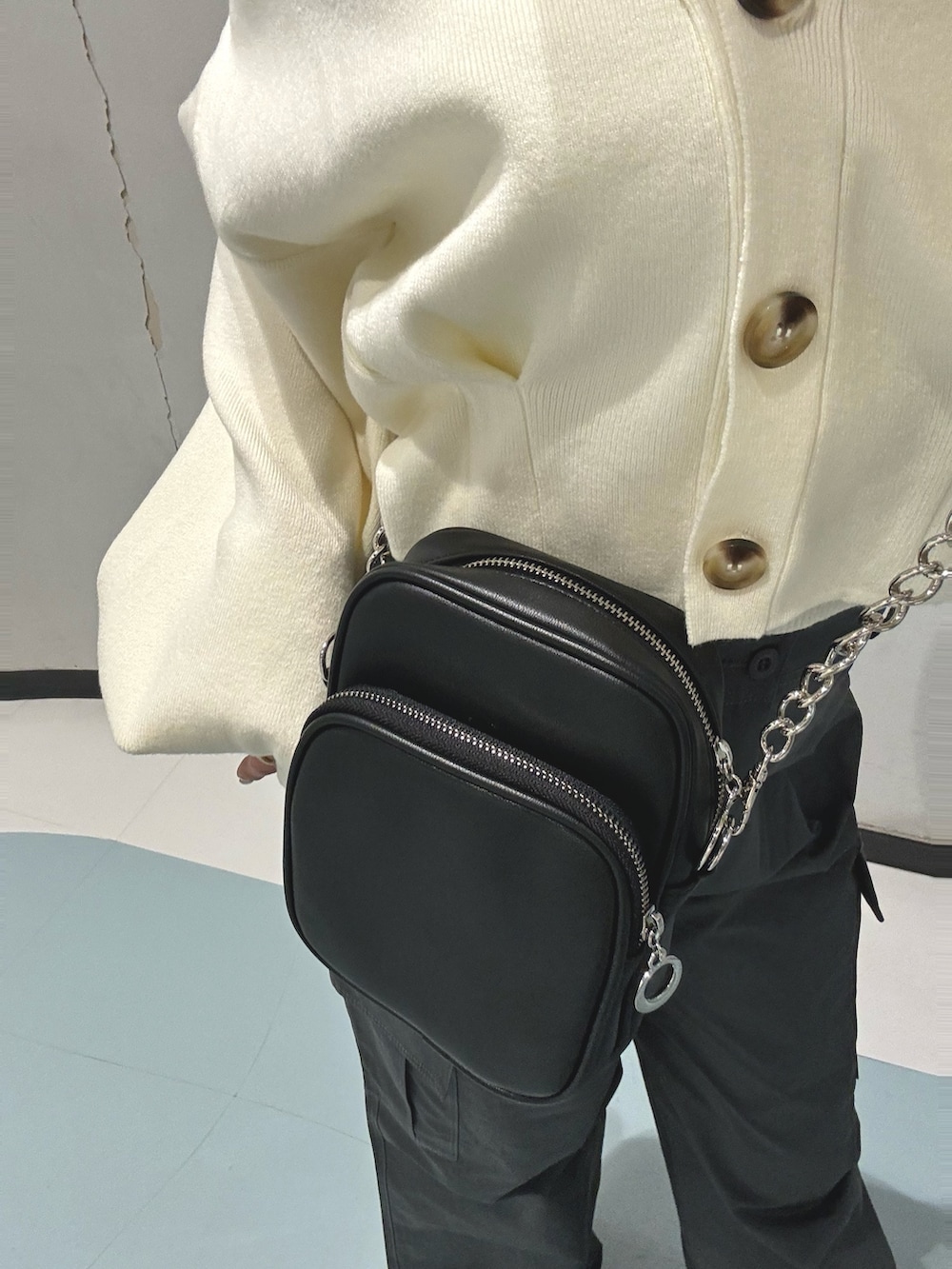 ブラック系のショルダーバッグ、グレー系のカーゴパンツ、ホワイト系のカーディガン/ボレロを着用したレディースの冬コーディネートの7枚目の写真