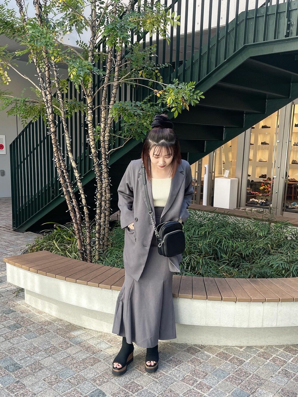 ブラック系のショルダーバッグ、グレー系のテーラードジャケット、グレー系のスカートを着用したレディースの冬コーディネートの2枚目の写真