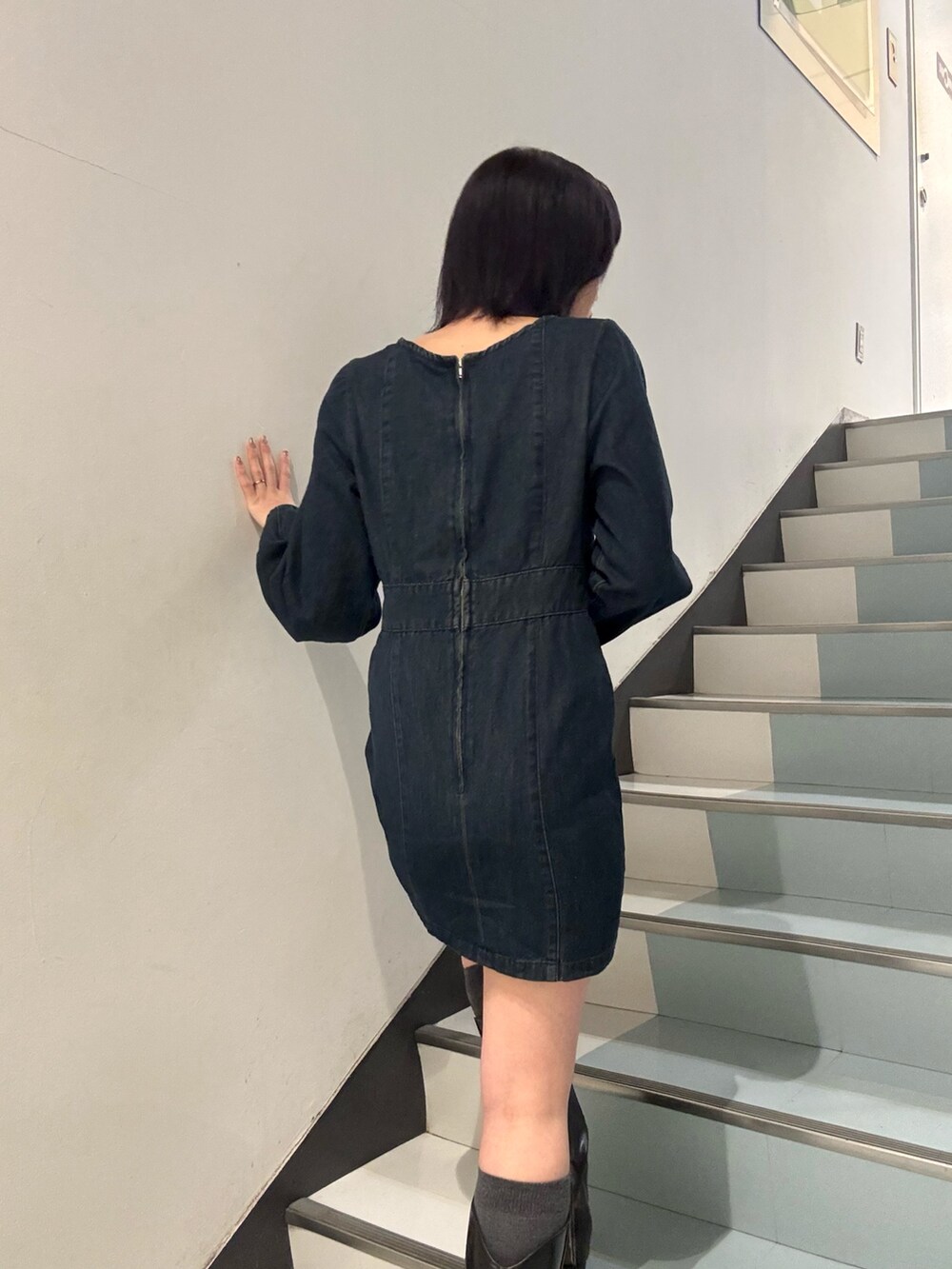 ブラック系のショルダーバッグ、ブラック系のブーツ、ブルー系のワンピースを着用したレディースの冬コーディネートの6枚目の写真