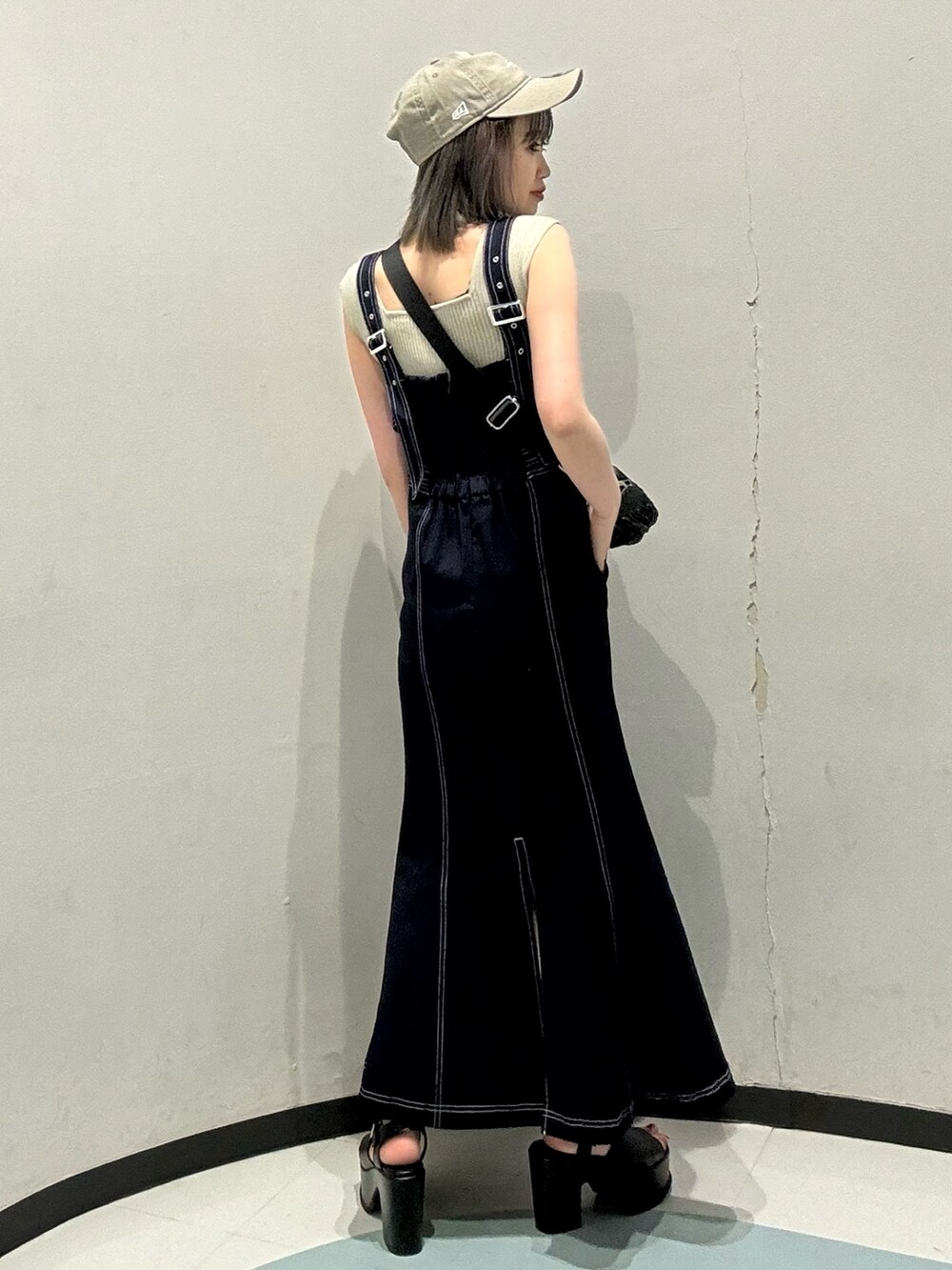 ベージュ系のニット/セーター、ブルー系のジャンパースカート、ブラック系のショルダーバッグを着用したレディースの春コーディネートの3枚目の写真