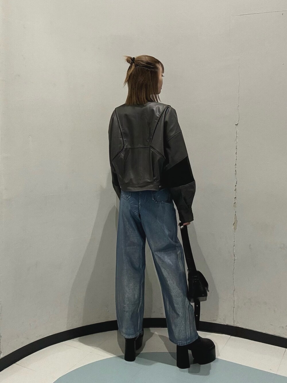 ブルー系のデニムパンツ、ブラック系のショルダーバッグ、グレー系のブルゾンを着用したレディースの冬コーディネートの3枚目の写真