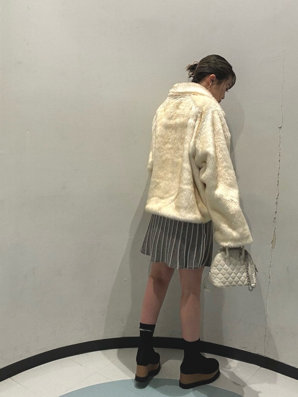 ホワイト系のブルゾン、ホワイト系のハンドバッグ、ブラック系のブーツを着用したレディースの冬コーディネートの3枚目の写真