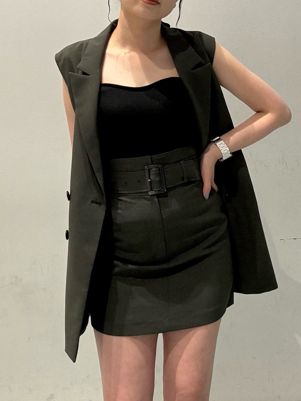 グレー系のベスト、グレー系のスカート、グレー系のショルダーバッグを着用したレディースの春コーディネートの5枚目の写真