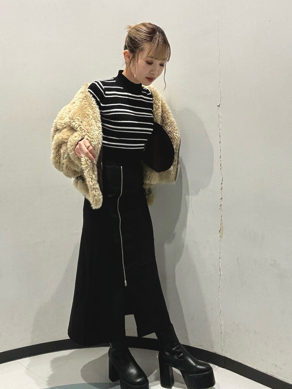 ブラック系のスカート、その他のニット/セーター、ブラウン系のムートンコートを着用したレディースの秋コーディネートの2枚目の写真