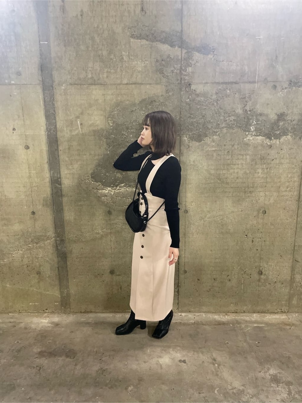 ブラック系のニット/セーター、ホワイト系のワンピース、ベージュ系のトレンチコートを着用したレディースの秋コーディネートの4枚目の写真