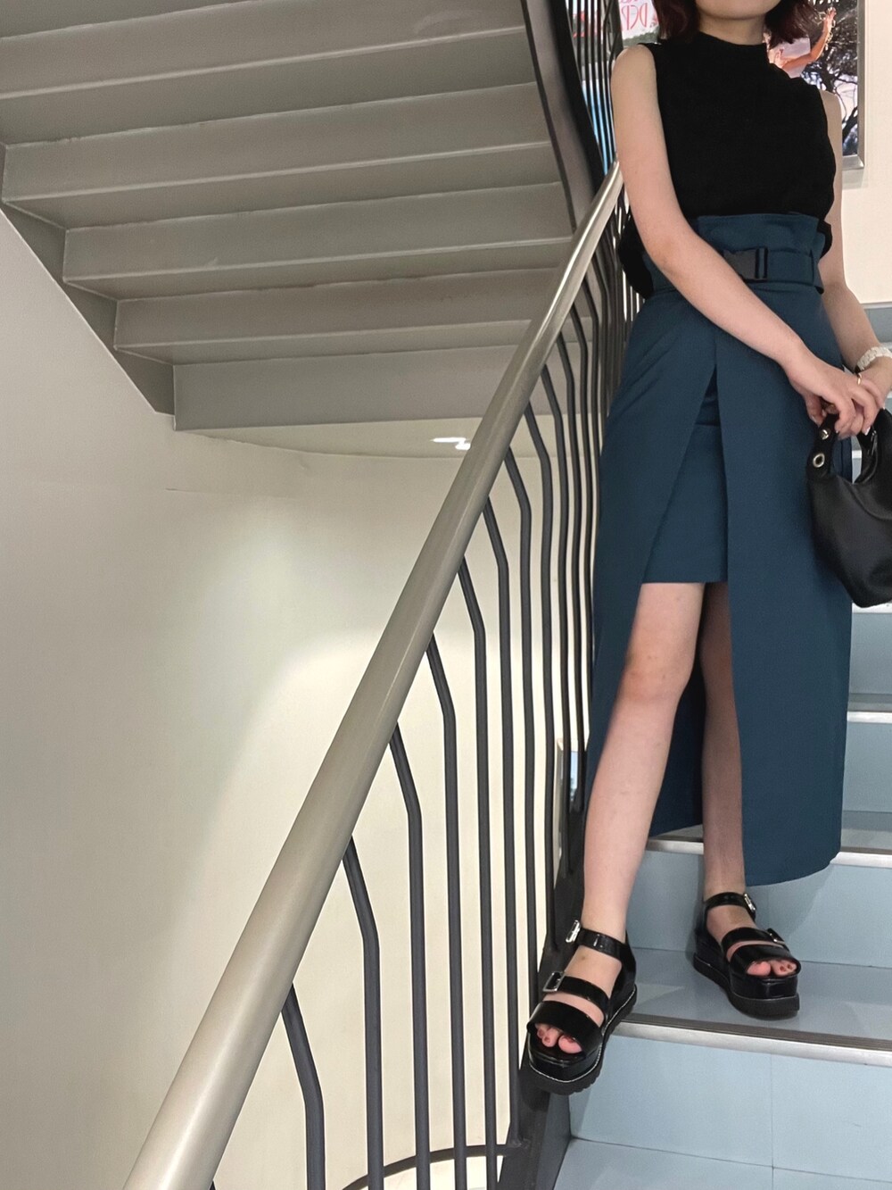 ブラック系のハンドバッグ、ブルー系のスカート、ブラック系のシャツ/ブラウスを着用したレディースの夏コーディネートの5枚目の写真