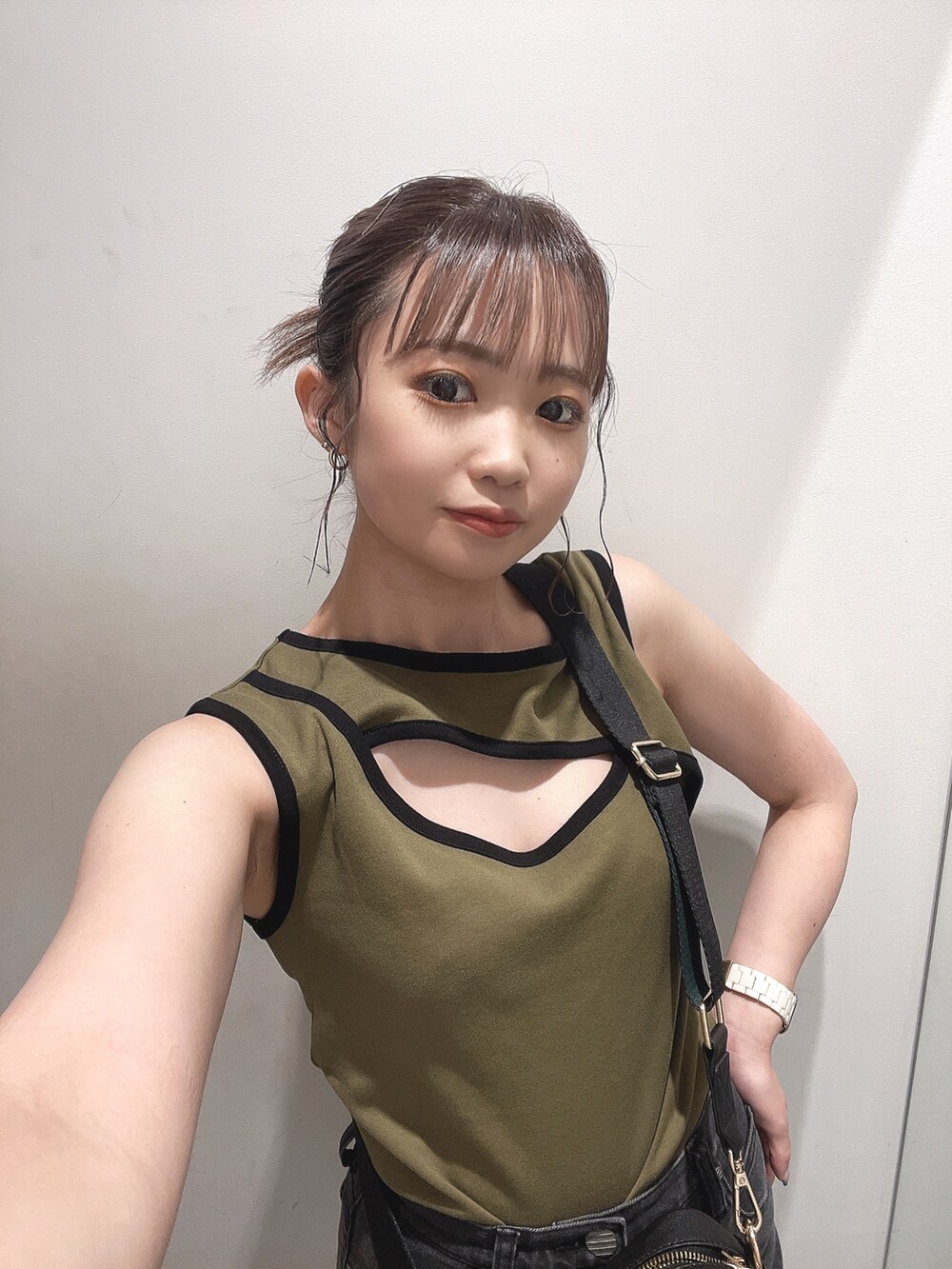 ブラック系のショルダーバッグ、グリーン系のタンクトップ、グレー系のデニムパンツを着用したレディースの夏コーディネートの3枚目の写真