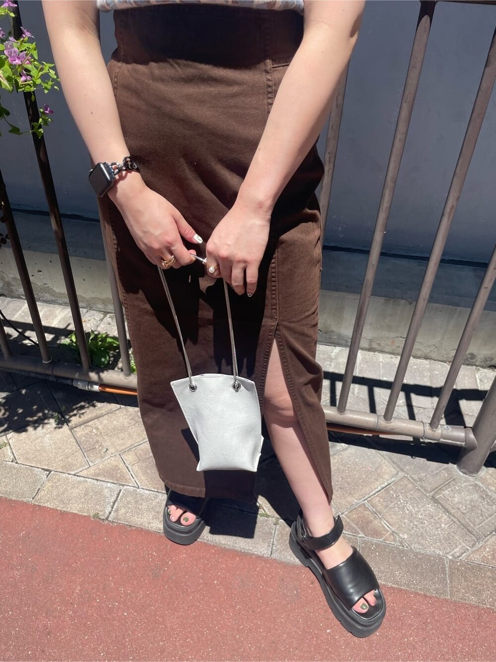 ホワイト系のショルダーバッグ、ブラウン系のブルゾン、ブラウン系のスカートを着用したレディースの夏コーディネートの2枚目の写真