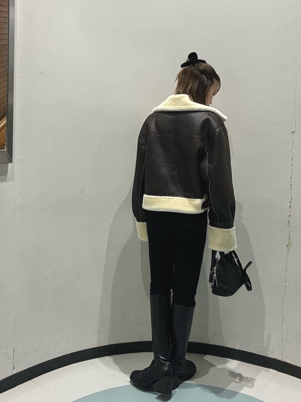 ブラック系のブーツ、ブラック系のハンドバッグ、ブラウン系のムートンコートを着用したレディースの冬コーディネートの2枚目の写真