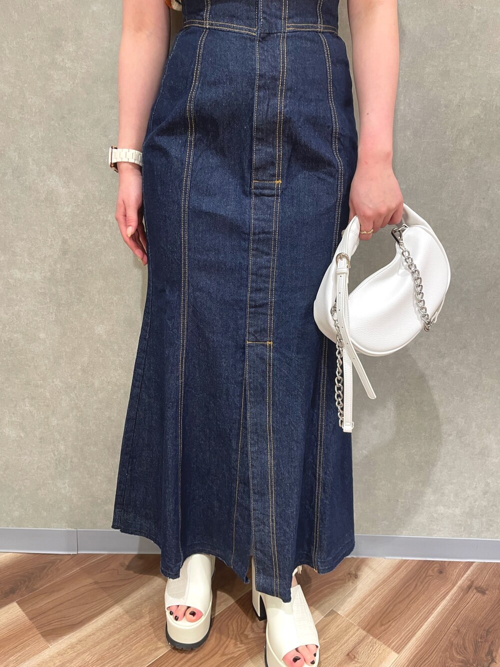 オレンジ系のカーディガン/ボレロ、ホワイト系のデニムスカート、ホワイト系のサンダルを着用したレディースの春コーディネートの6枚目の写真