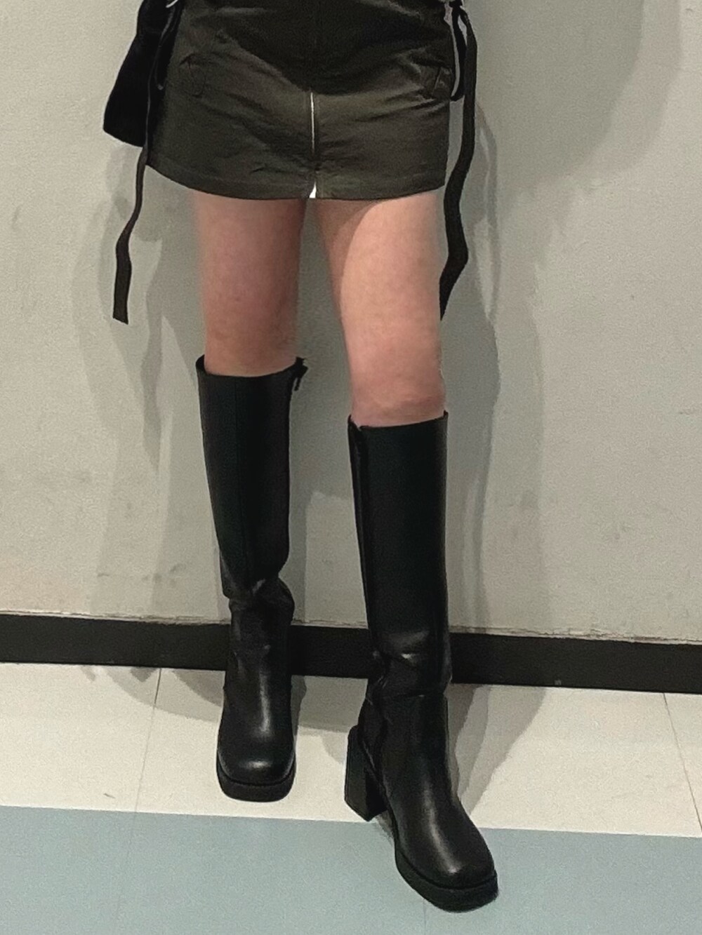 ブラック系のブーツ、ブラック系のTシャツ/カットソー、ベージュ系のスカートを着用したレディースの冬コーディネートの6枚目の写真