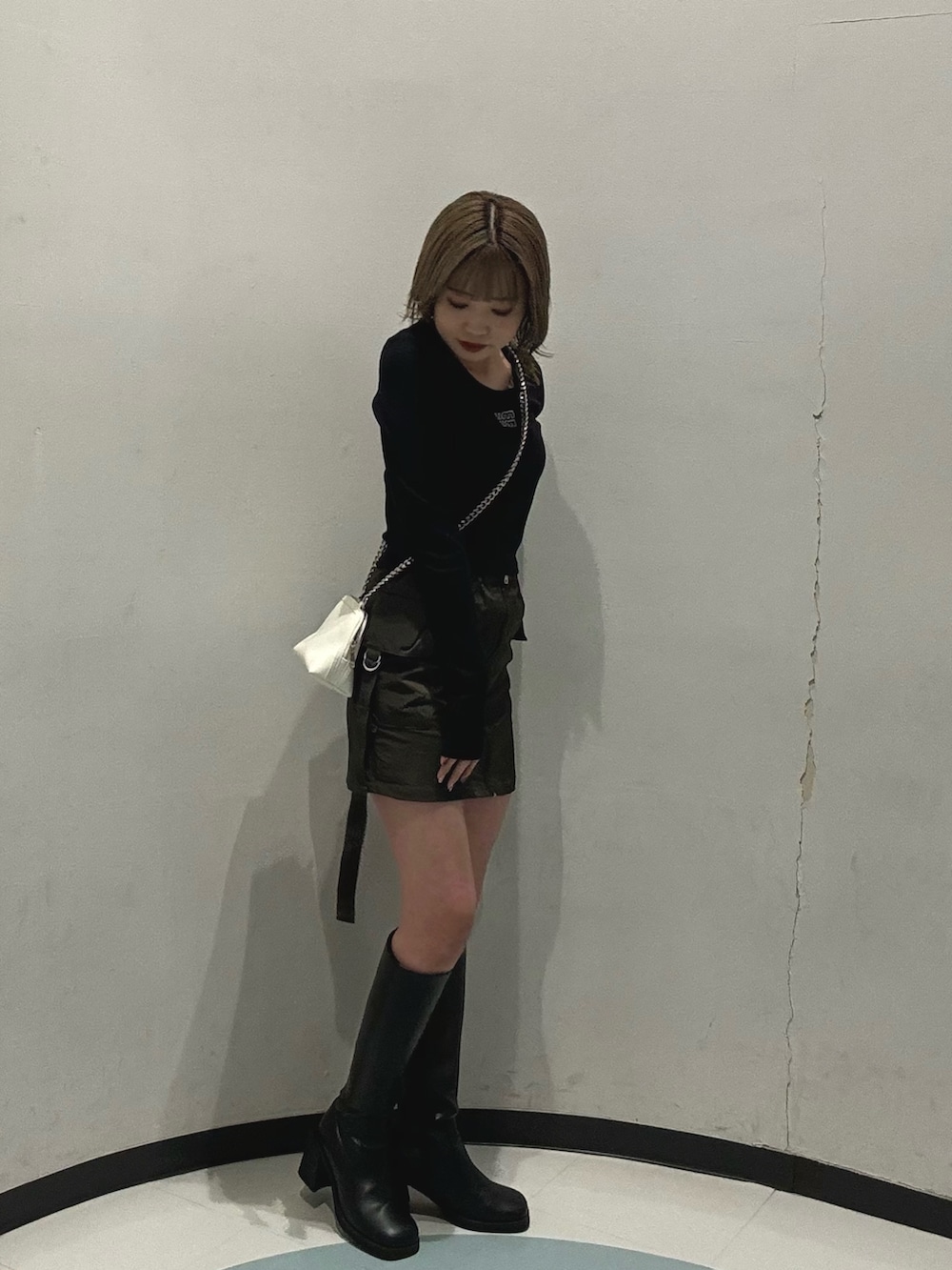 ブラック系のブーツ、ブラック系のTシャツ/カットソー、ベージュ系のスカートを着用したレディースの冬コーディネートの2枚目の写真